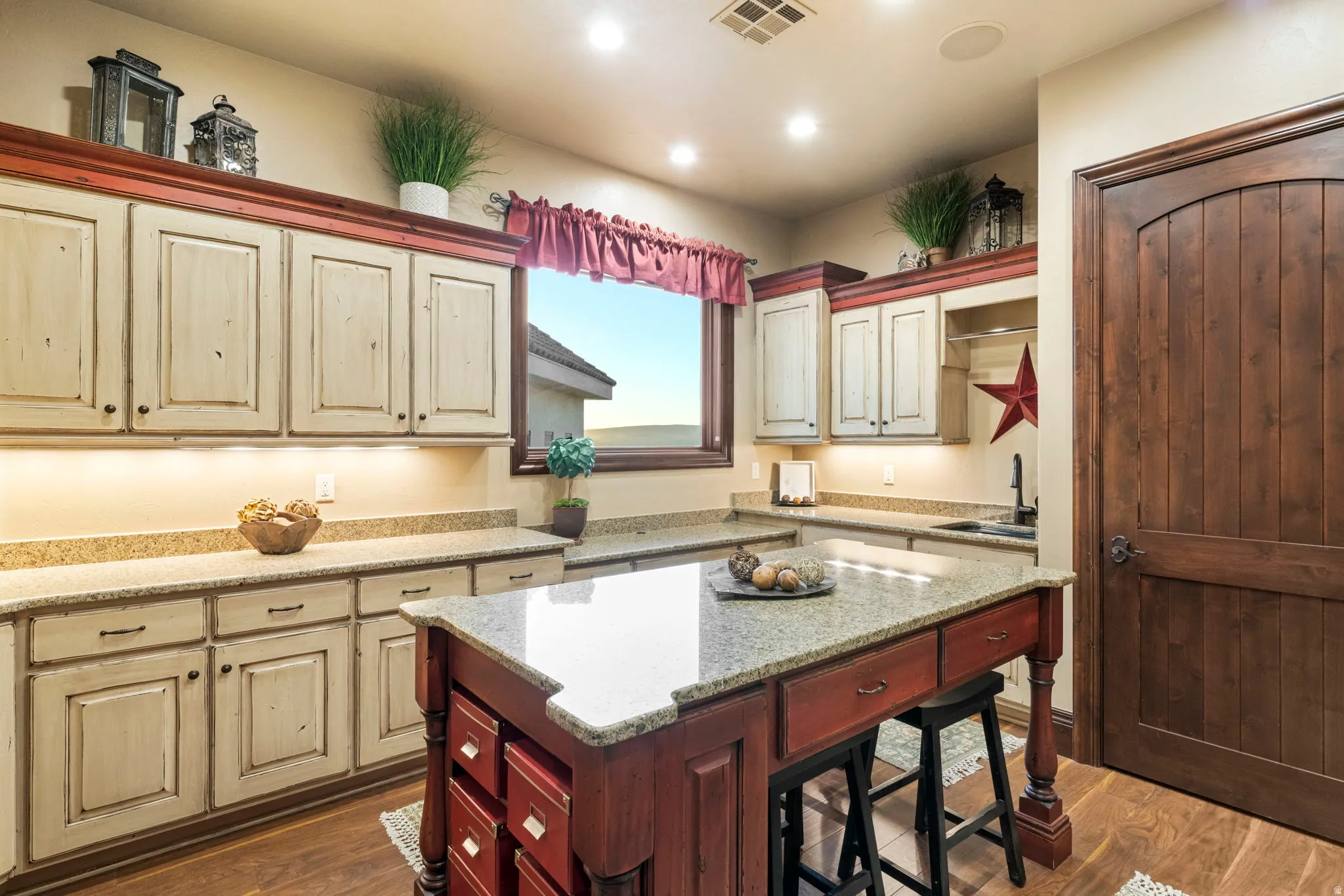 Kitchen featuring dark wood finished floors, light stone countertops, a breakfast bar, a center island, and recessed lighting