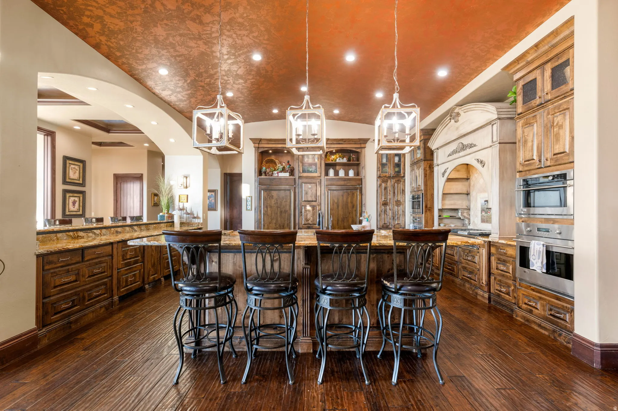 Kitchen featuring recessed lighting, lofted ceiling, hanging light fixtures, a kitchen bar, and light stone countertops