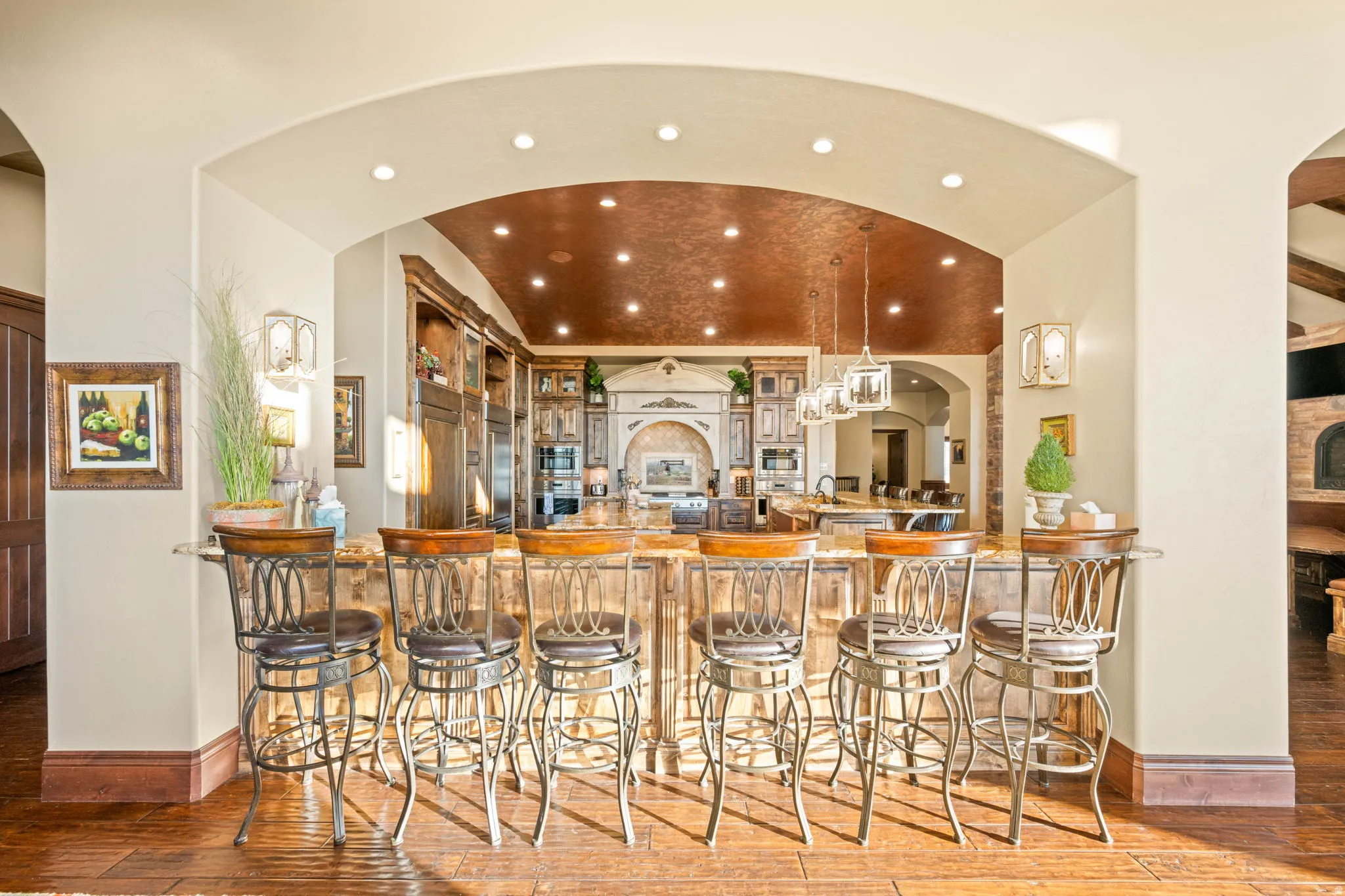 Bar featuring arched walkways, hanging light fixtures, recessed lighting, dark stone counters, and light wood-type flooring