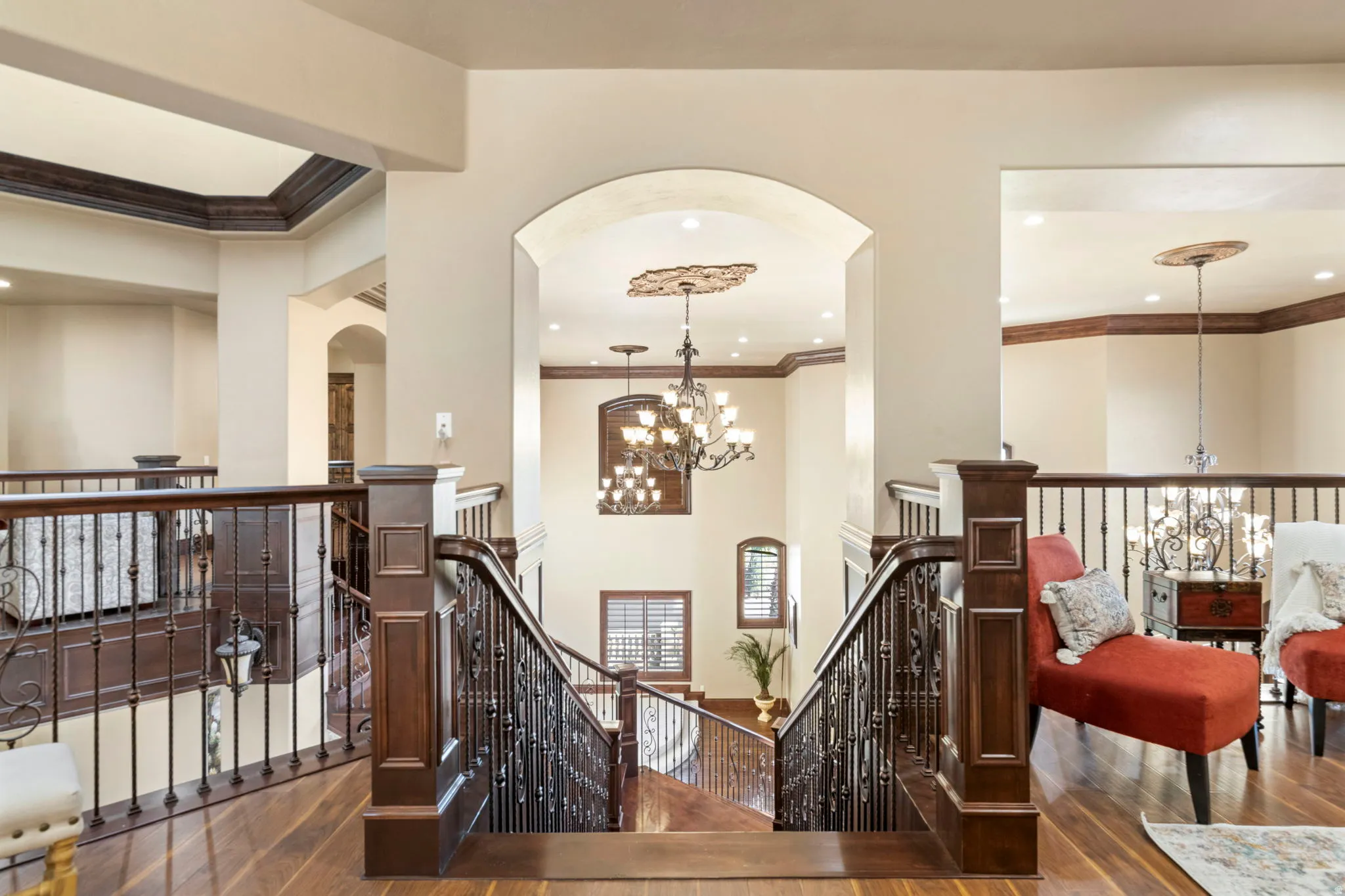 Corridor featuring an upstairs landing, arched walkways, a chandelier, dark wood finished floors, and crown molding