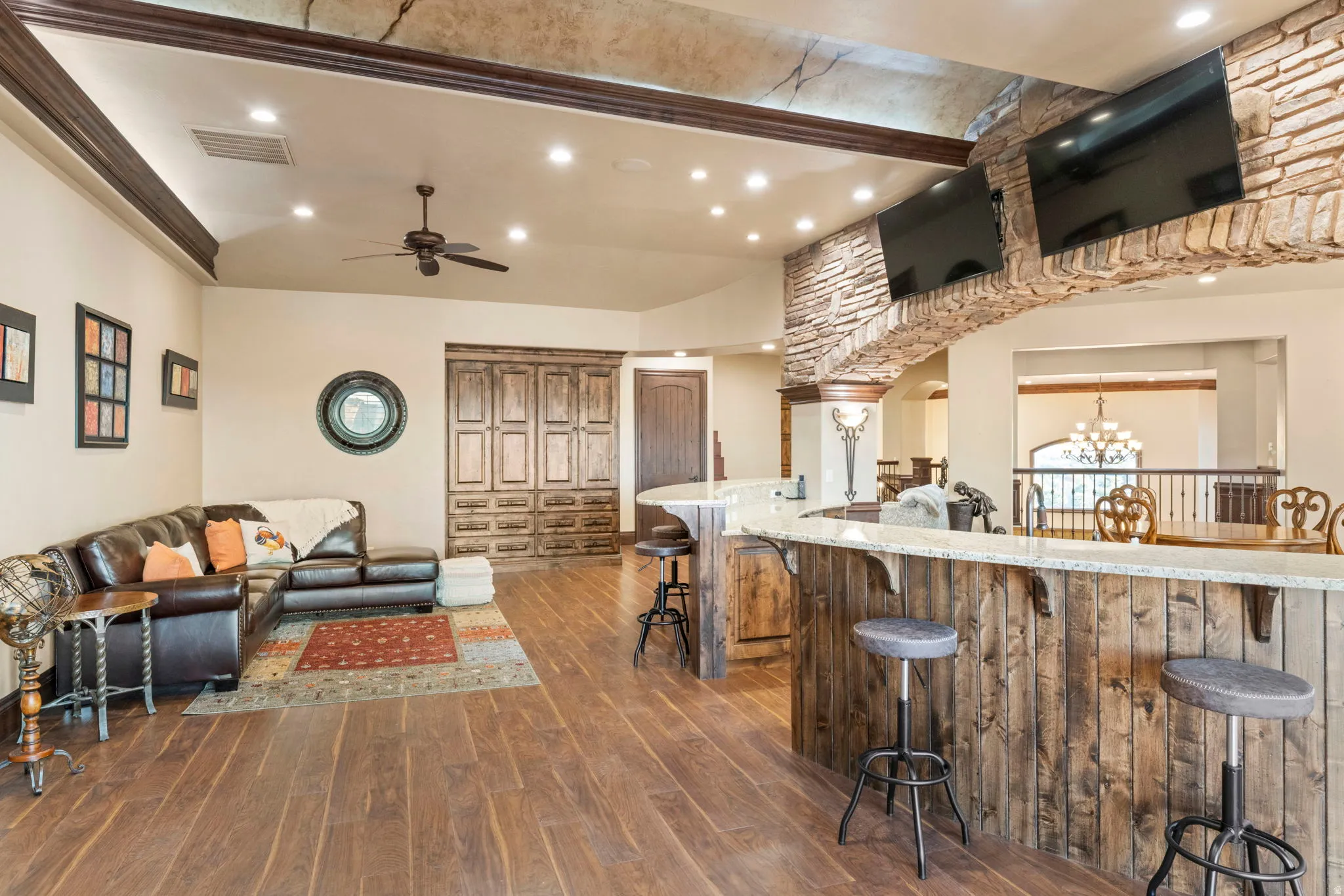 Kitchen with recessed lighting, dark wood finished floors, a kitchen bar, a chandelier, and light stone counters
