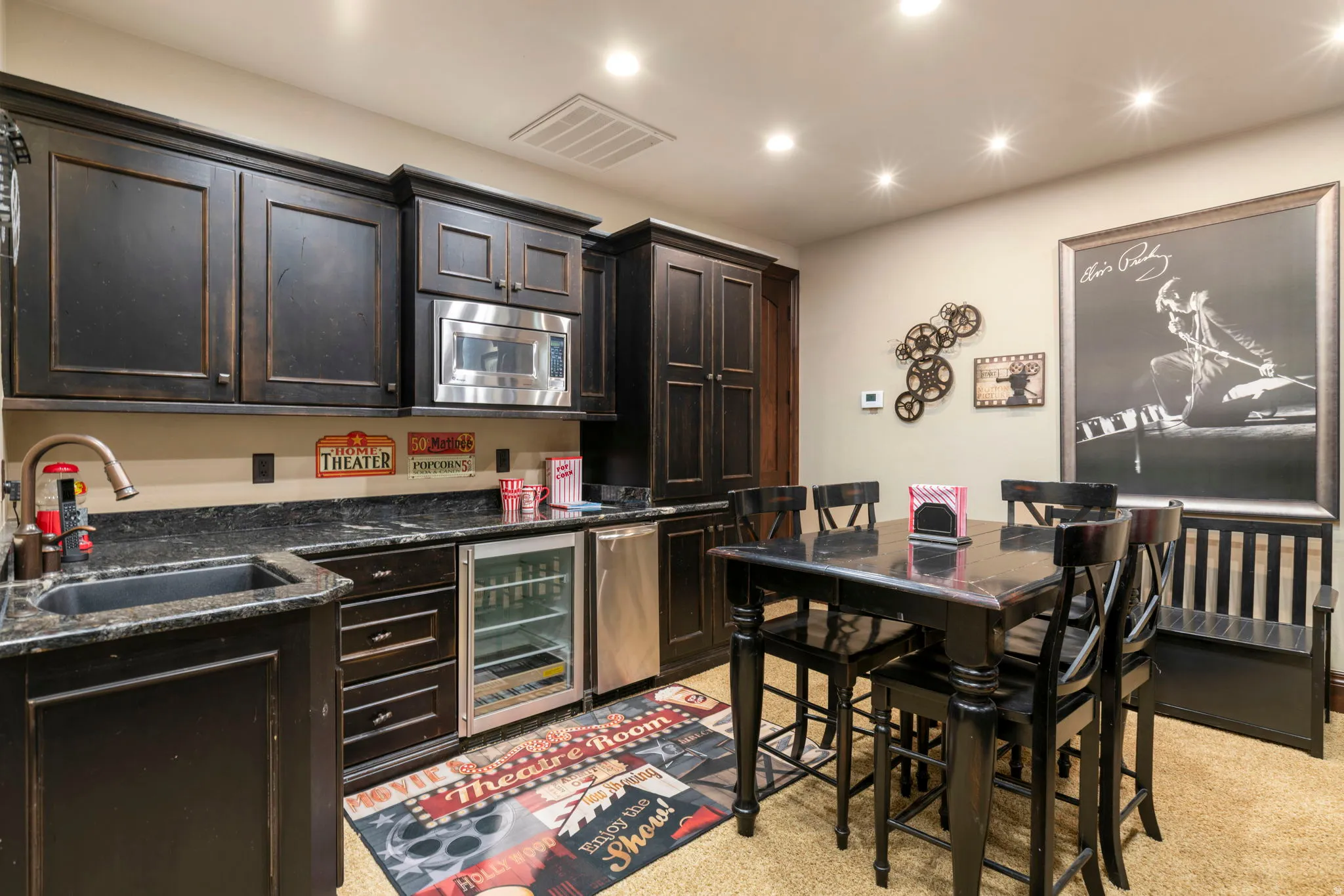 Kitchen featuring dark stone counters, dark brown cabinets, beverage cooler, stainless steel microwave, and recessed lighting