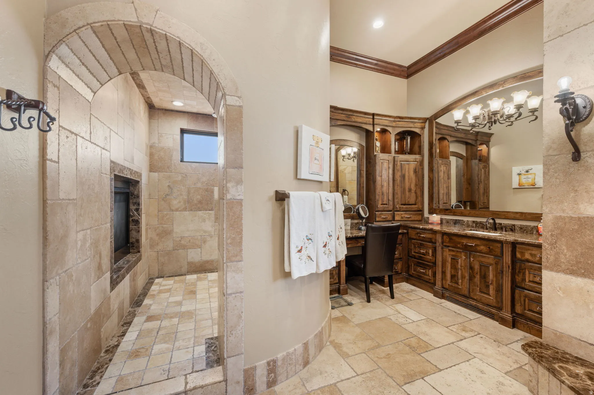 Bathroom featuring vanity, stone tile flooring, walk in shower, and crown molding