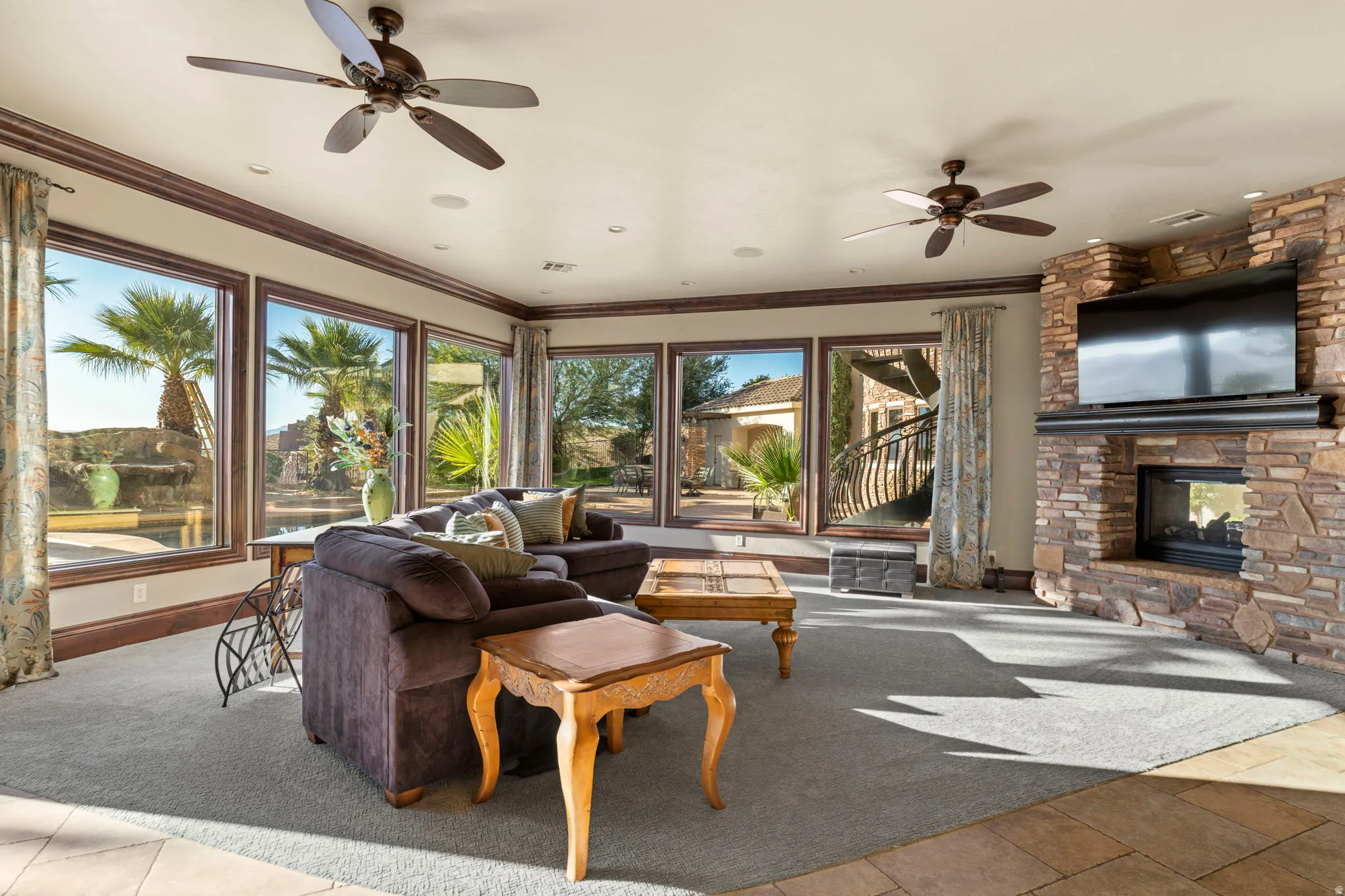 Carpeted living area with ornamental molding, a fireplace, tile patterned floors, a ceiling fan, and a water view