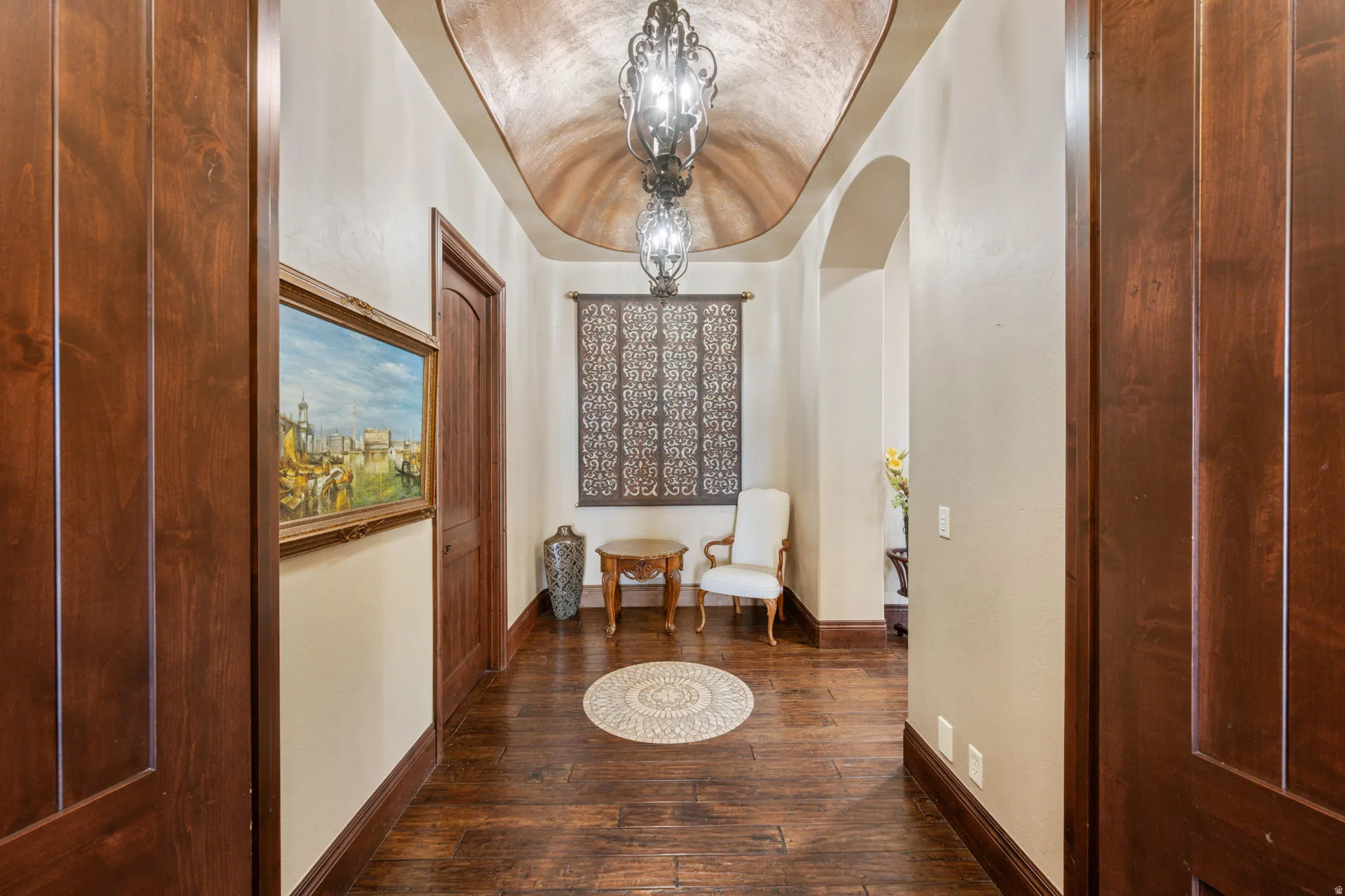 Corridor featuring a chandelier, dark wood-style flooring, arched walkways, and lofted ceiling