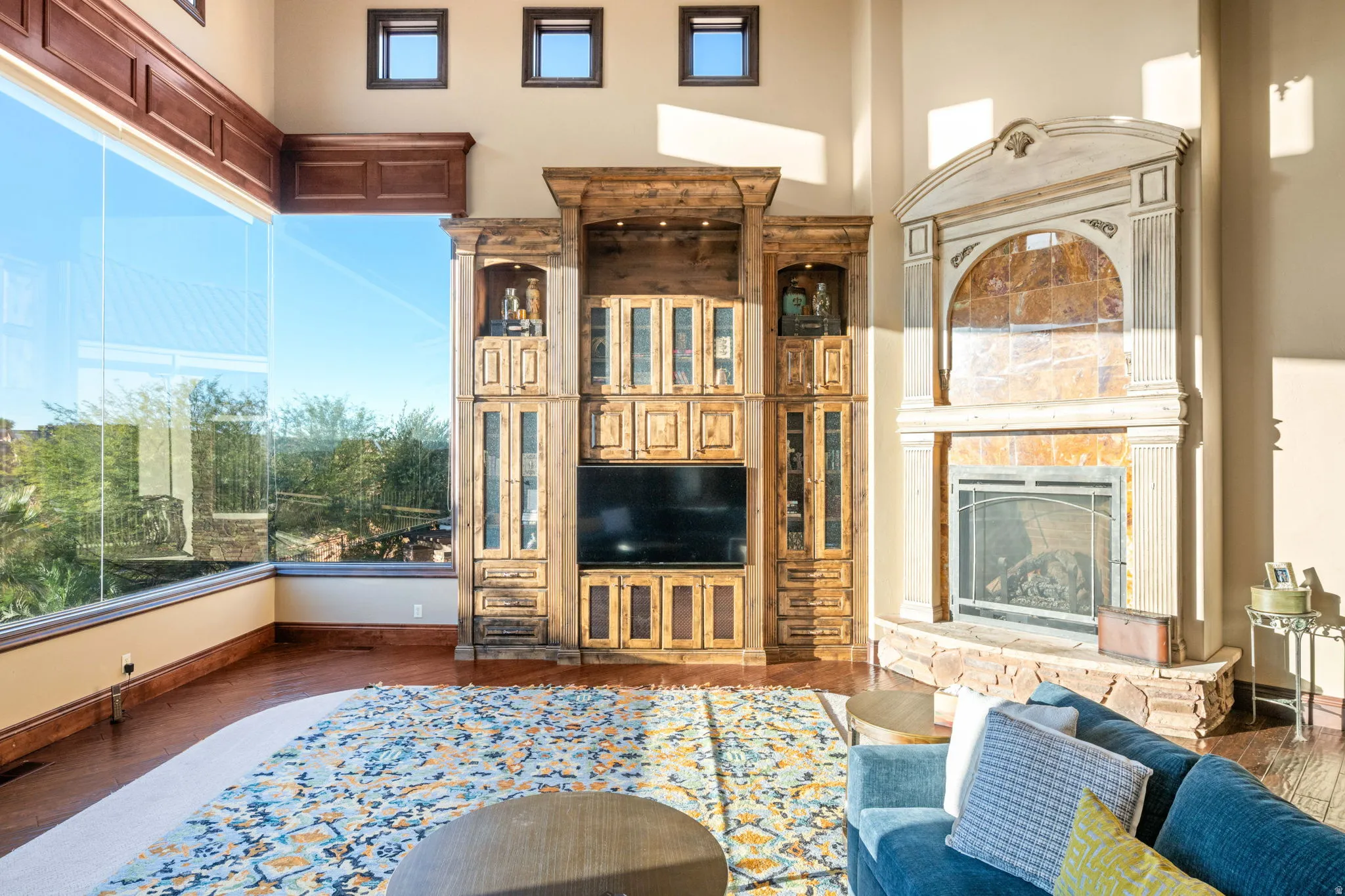 Living room with plenty of natural light, dark wood-style floors, a fireplace with raised hearth, and a high ceiling