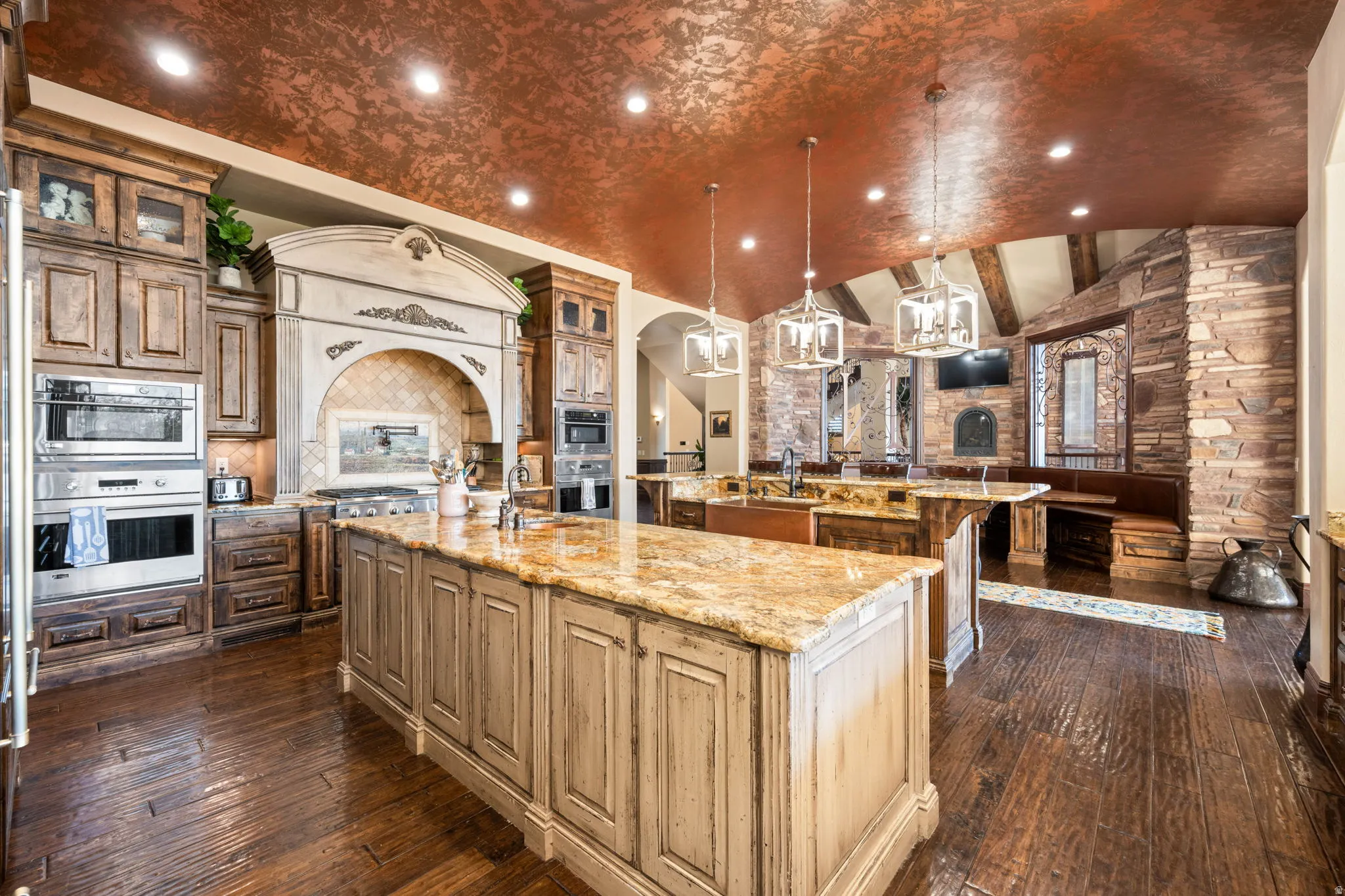Kitchen featuring lofted ceiling, decorative light fixtures, light stone countertops, glass insert cabinets, and recessed lighting