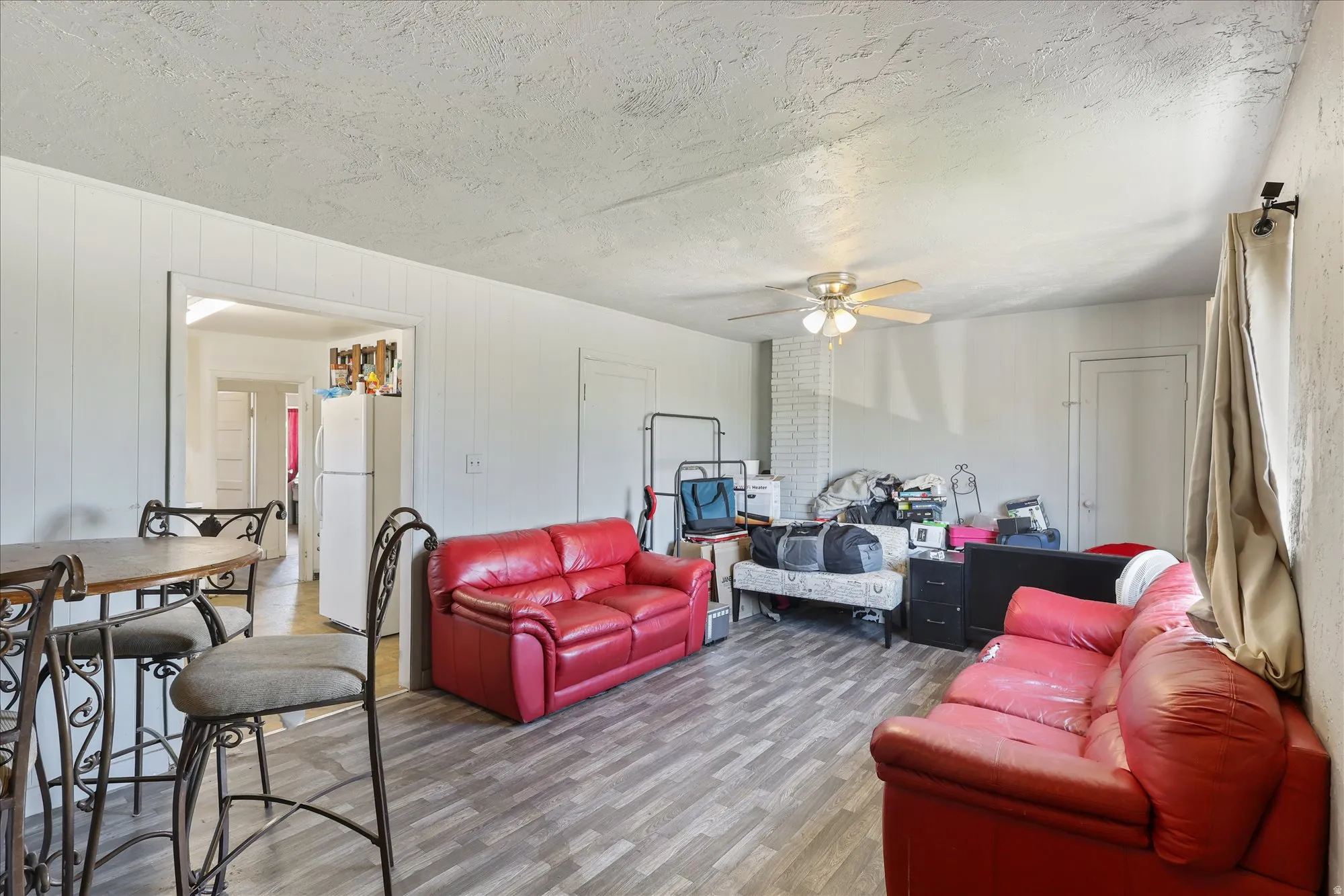 Living area featuring ceiling fan, wood finished floors, and a textured ceiling