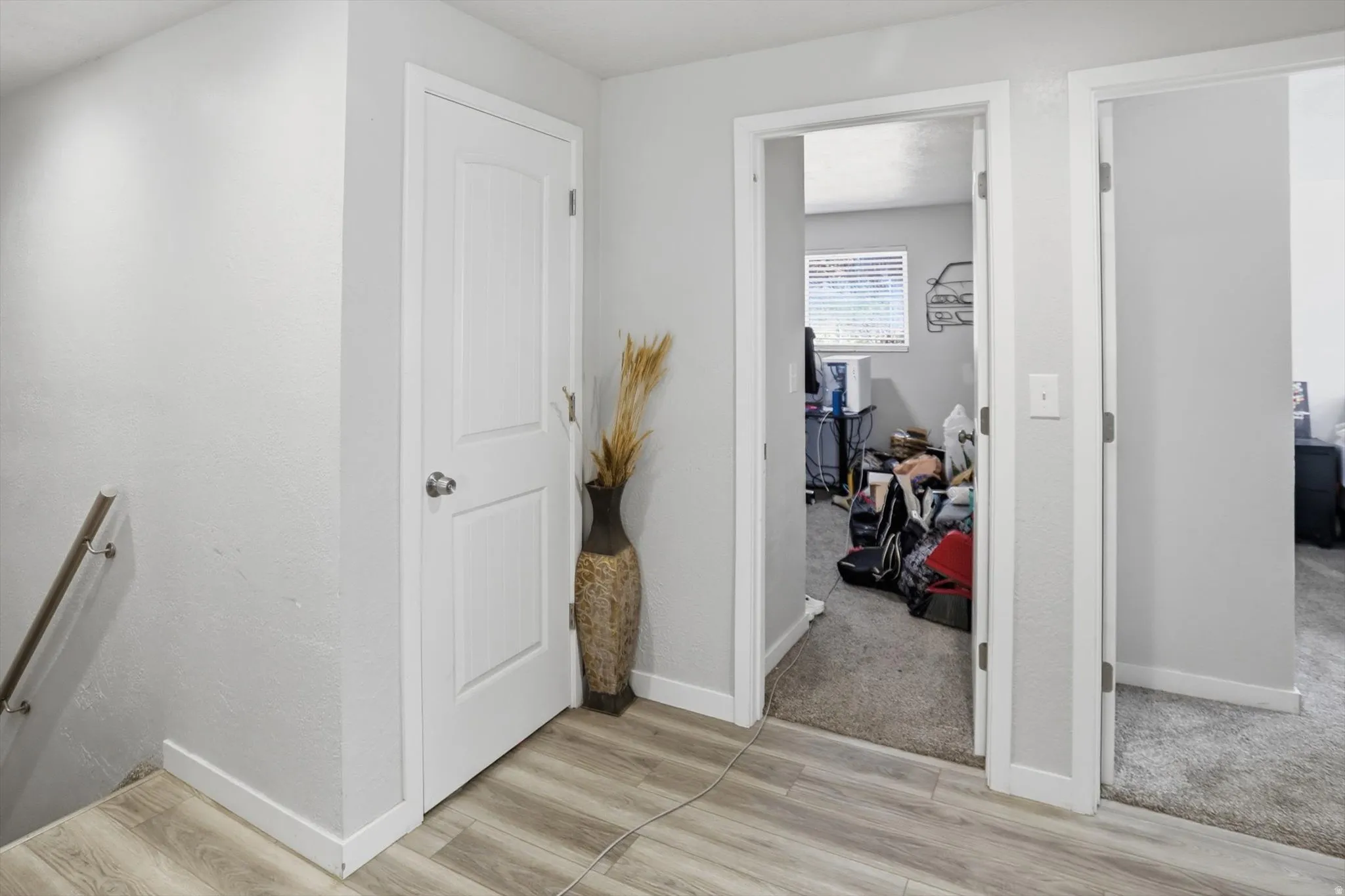 Hall with light wood-style flooring, light colored carpet, and an upstairs landing