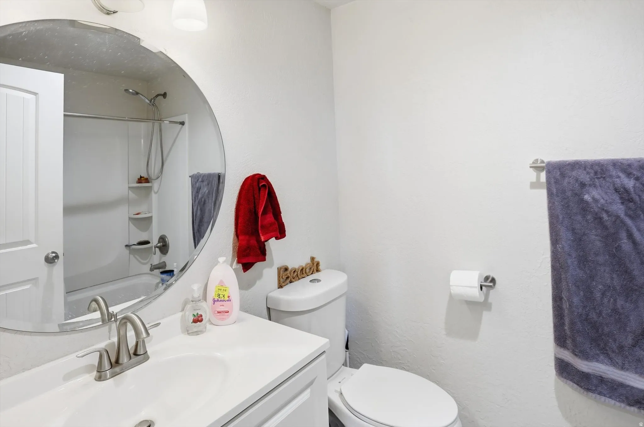 Full bathroom featuring vanity, shower / tub combination, and a textured wall