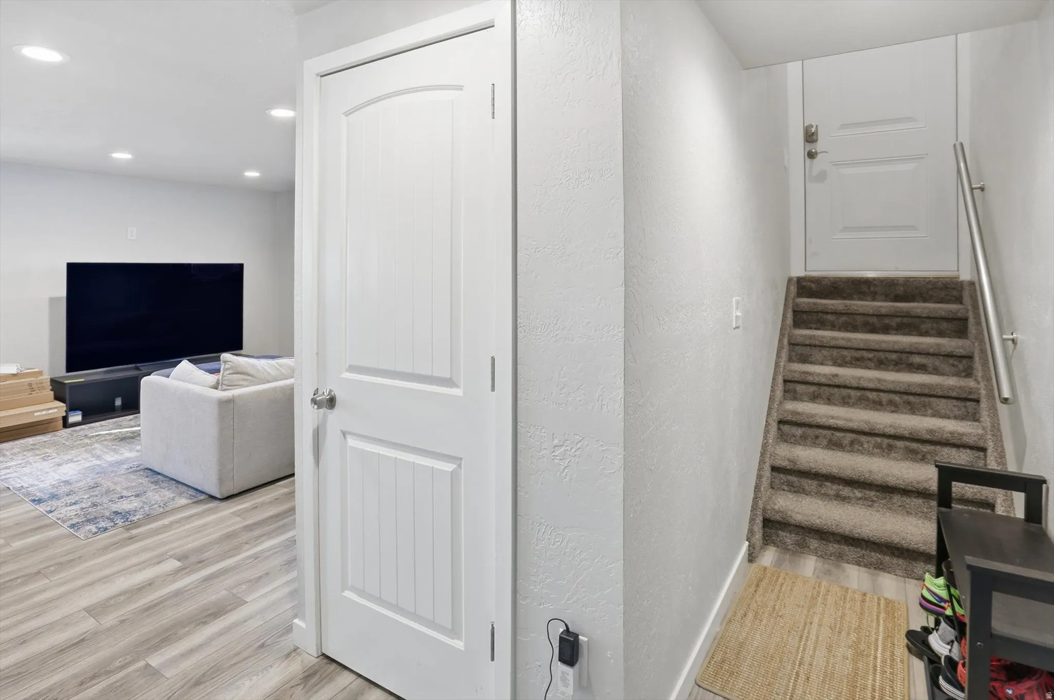 Stairs with a textured wall, wood finished floors, and recessed lighting