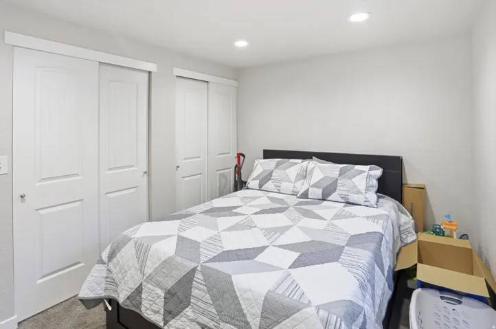 Bedroom with two closets, recessed lighting, and dark colored carpet