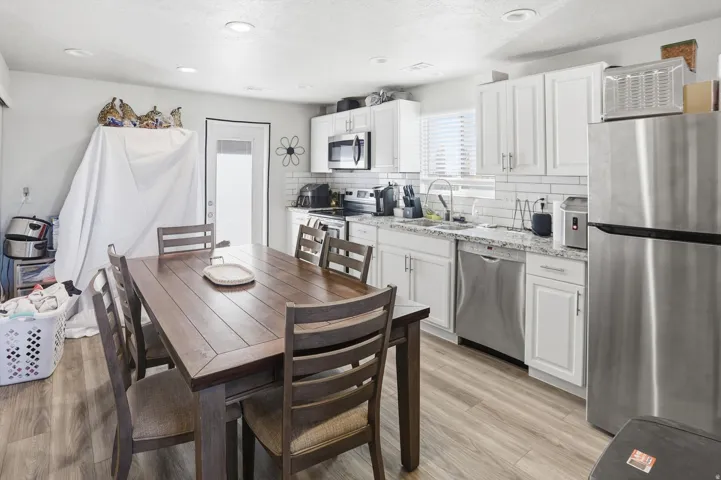 Kitchen featuring stainless steel appliances, white cabinetry, light stone countertops, tasteful backsplash, and WALKOUT TO DECK
