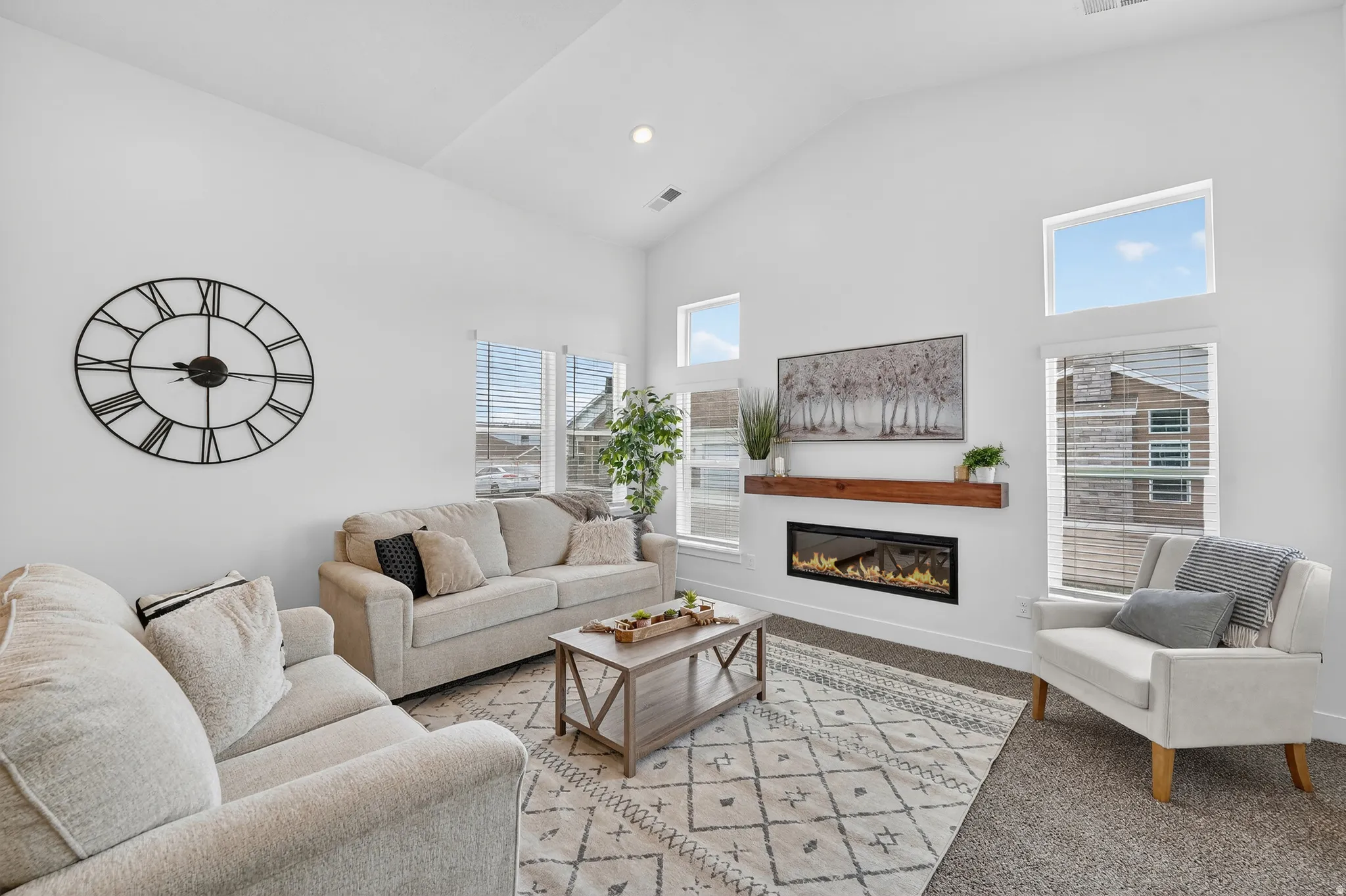Living room featuring a glass covered fireplace, vaulted ceiling, recessed lighting.
