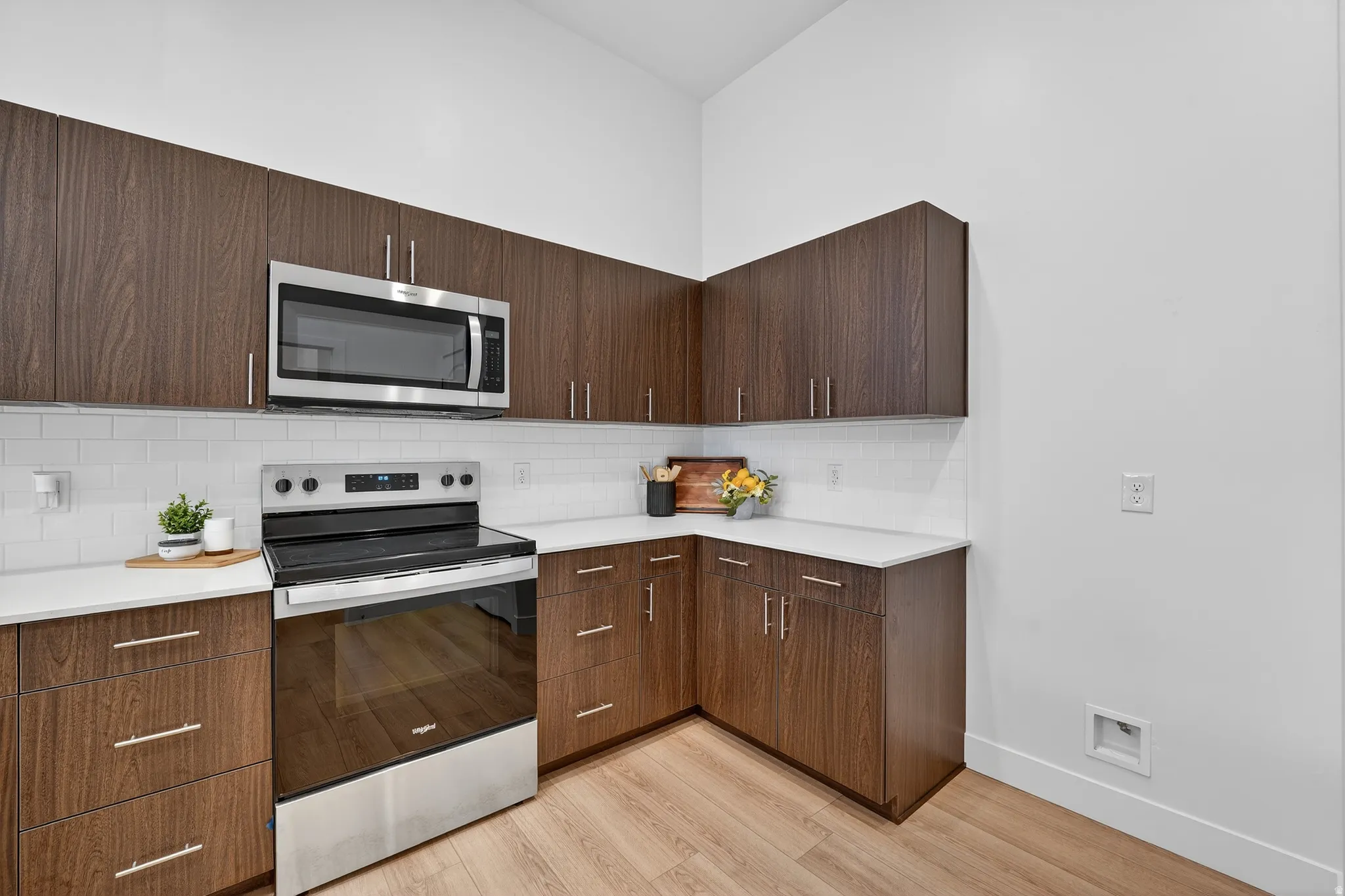 Kitchen featuring dark wood finish cabinets, a peninsula, modern cabinets, stainless steel appliances, and decorative pendent lights.