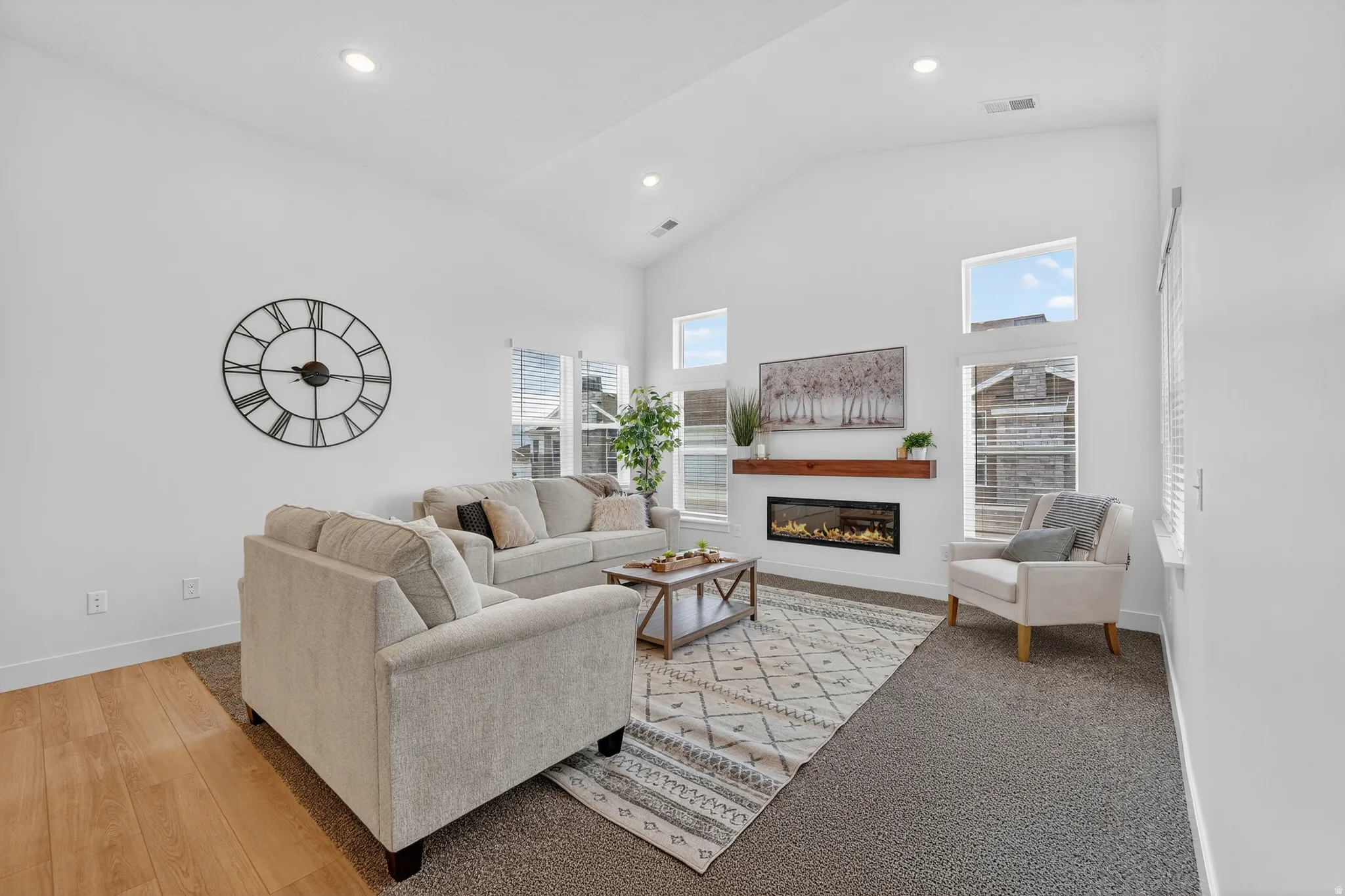 Living room featuring a glass covered fireplace, vaulted ceiling, recessed lighting.