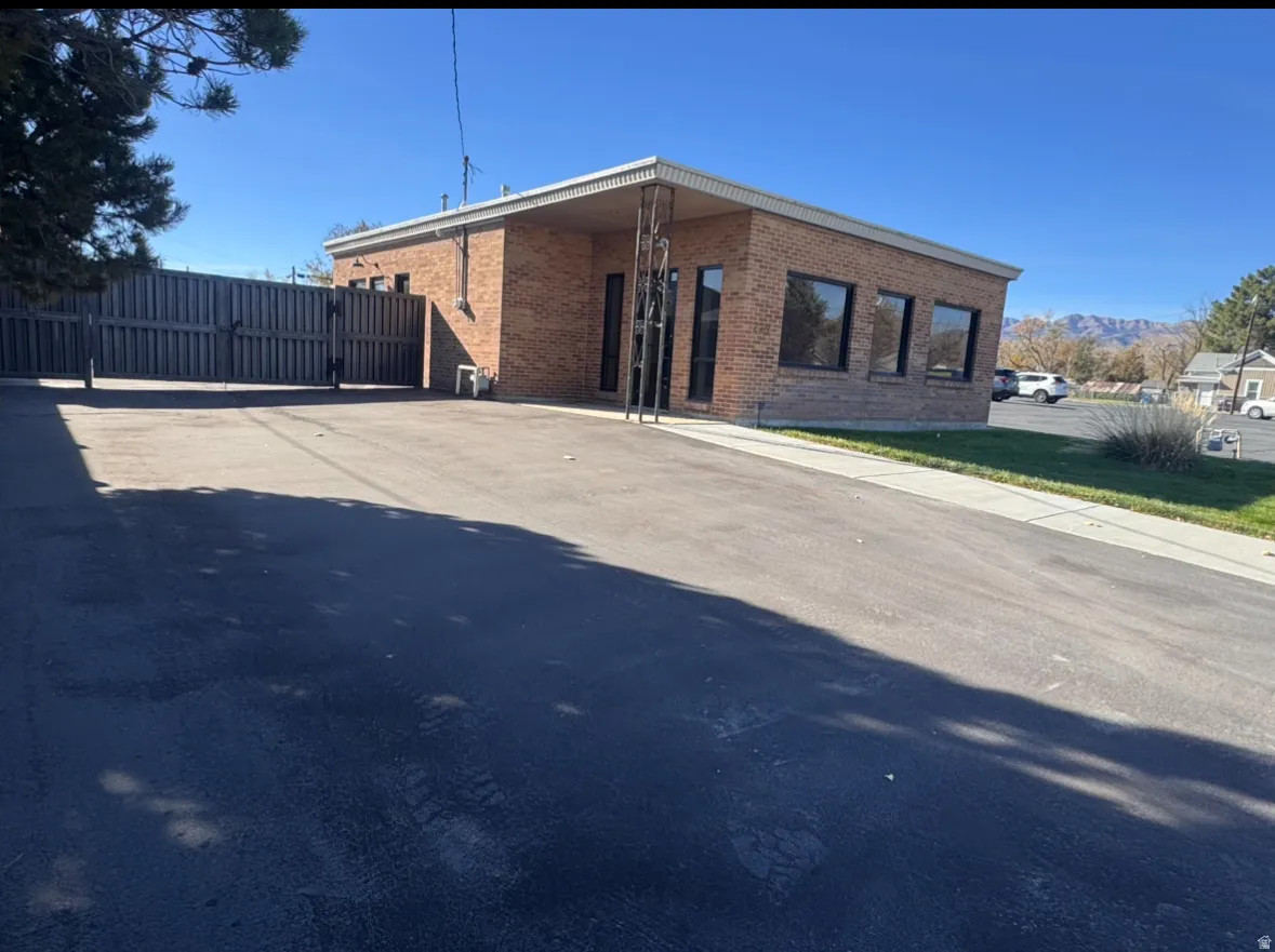 View of front of home with brick siding, a gate, concrete driveway, and a carport