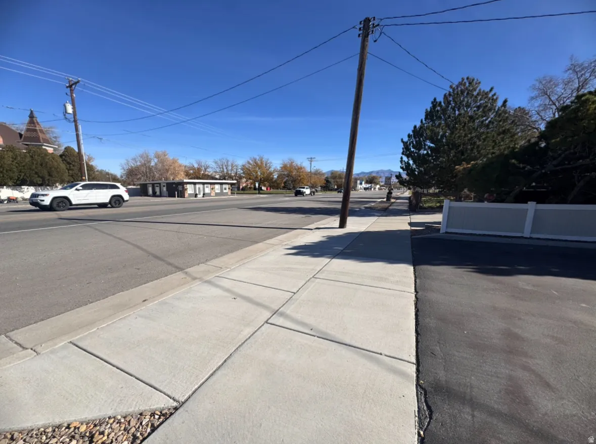 View of asphalt road featuring sidewalks and curbs