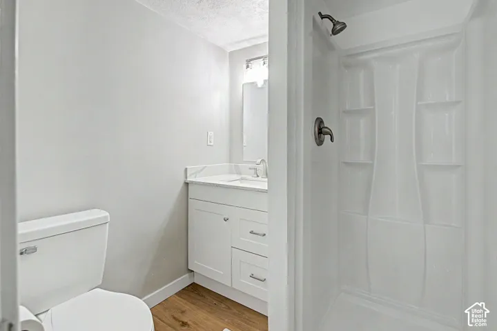 White vanity with a stone-finish countertop, undermount sink, and chrome faucet