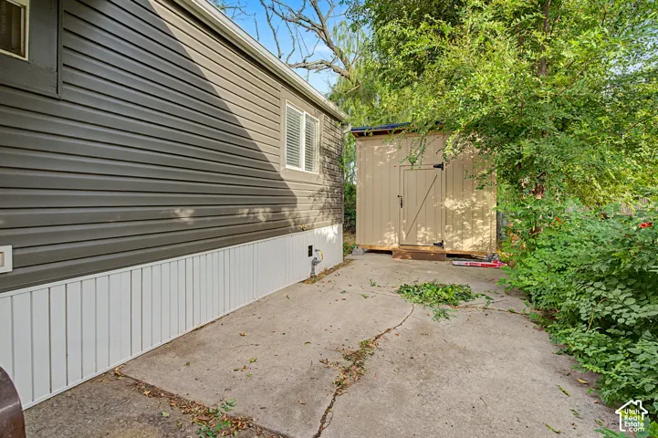 Exterior siding, white vertical skirting, and a detached shed