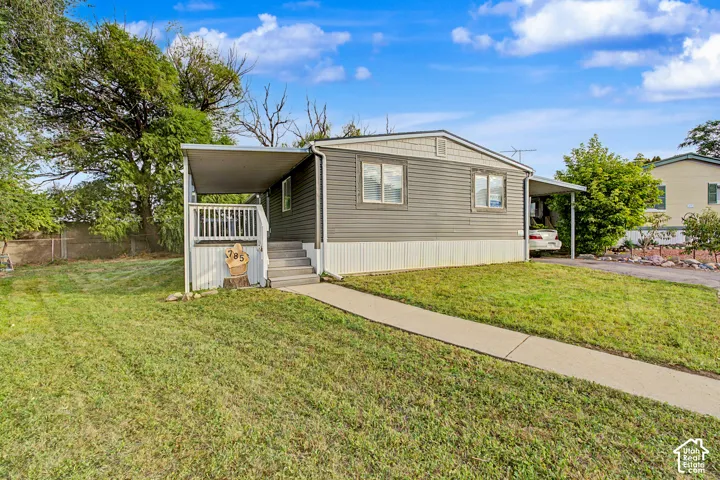 Exterior features include gray horizontal siding, white trim, a covered porch with white railing, a covered carport, and a concrete walkway