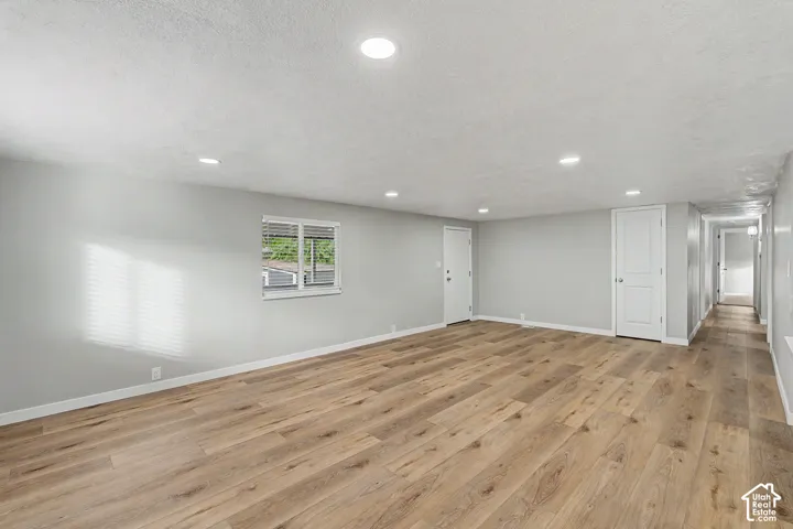 Expansive room featuring wood-finish flooring, recessed lighting, and a window with horizontal blinds