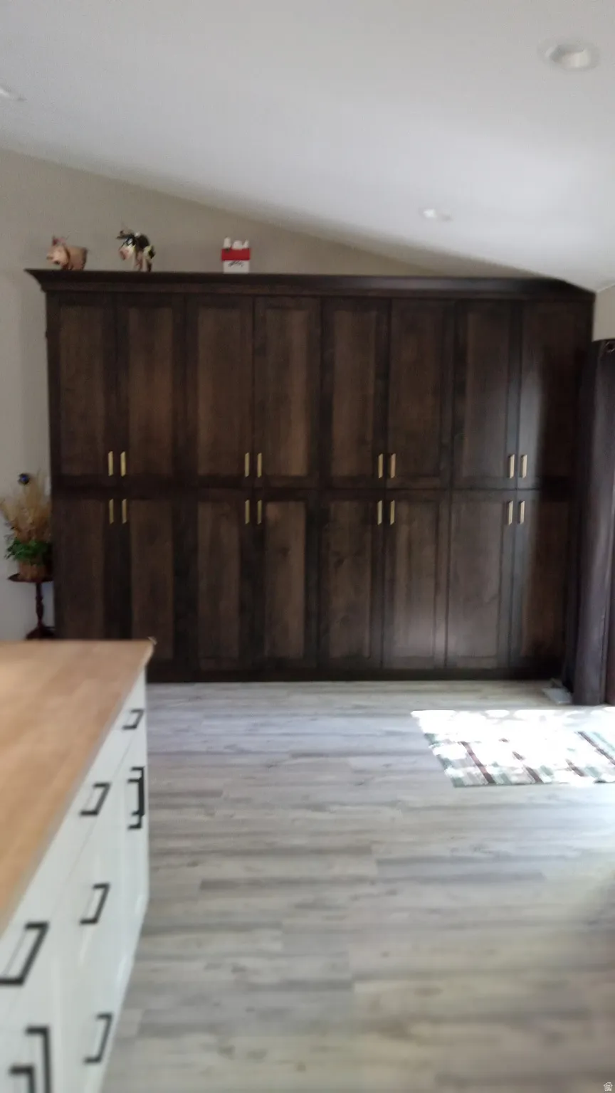 Interior space featuring light wood-style floors, dark brown cabinetry, white cabinetry, and wood counters