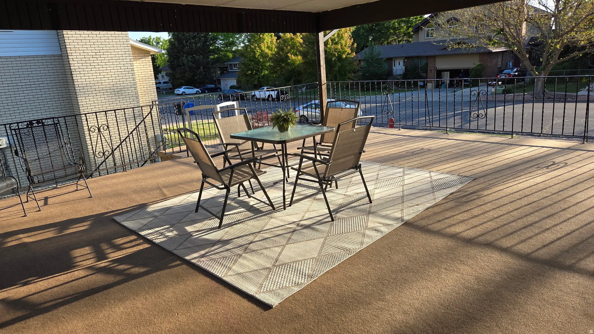 Spacious covered patio with brown outdoor carpeting and decorative black metal railing