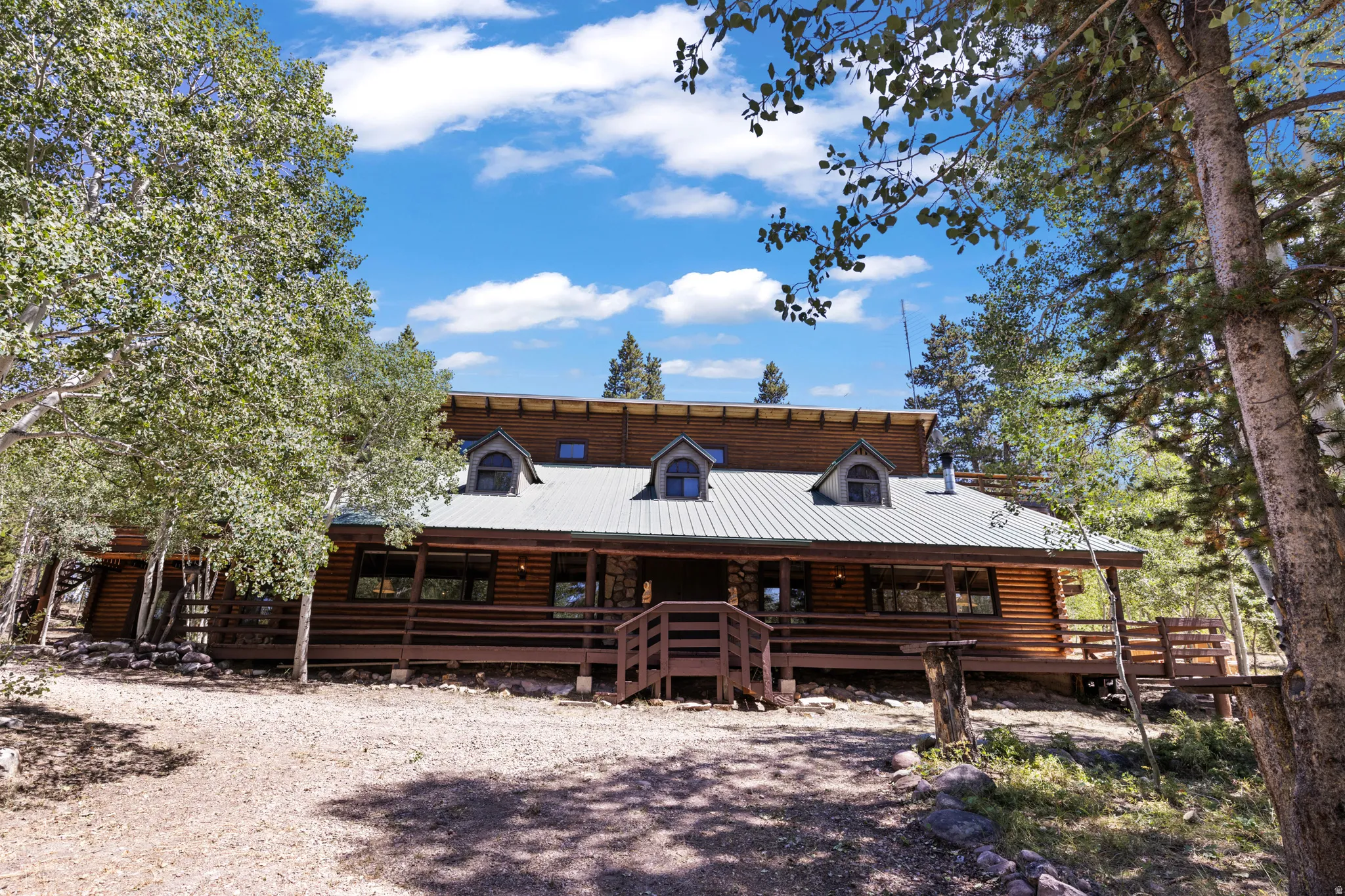 View of front facade featuring a metal roof, log exterior, and covered porch