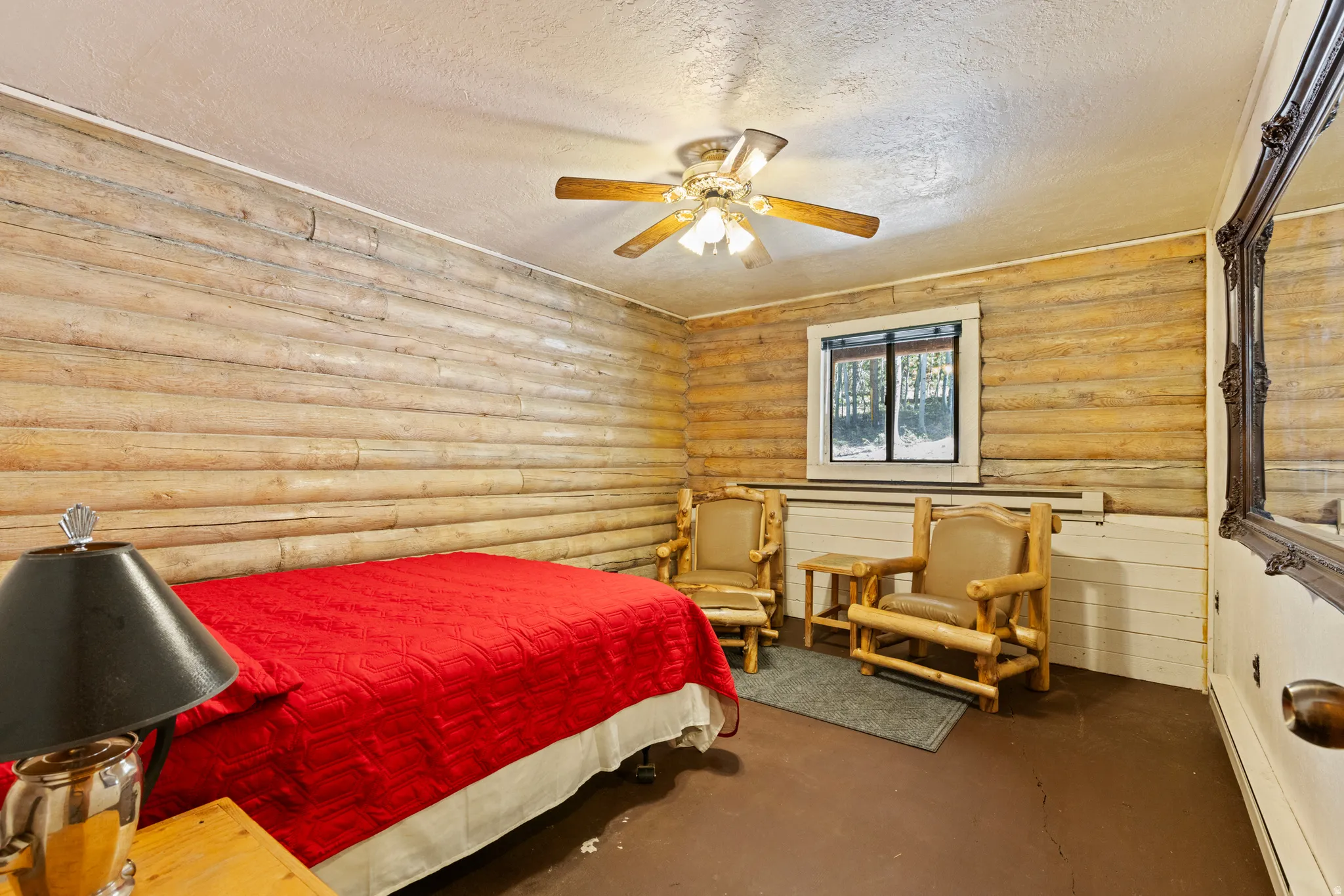 Bedroom featuring a textured ceiling, log walls, a baseboard heating unit, ceiling fan, and concrete floors