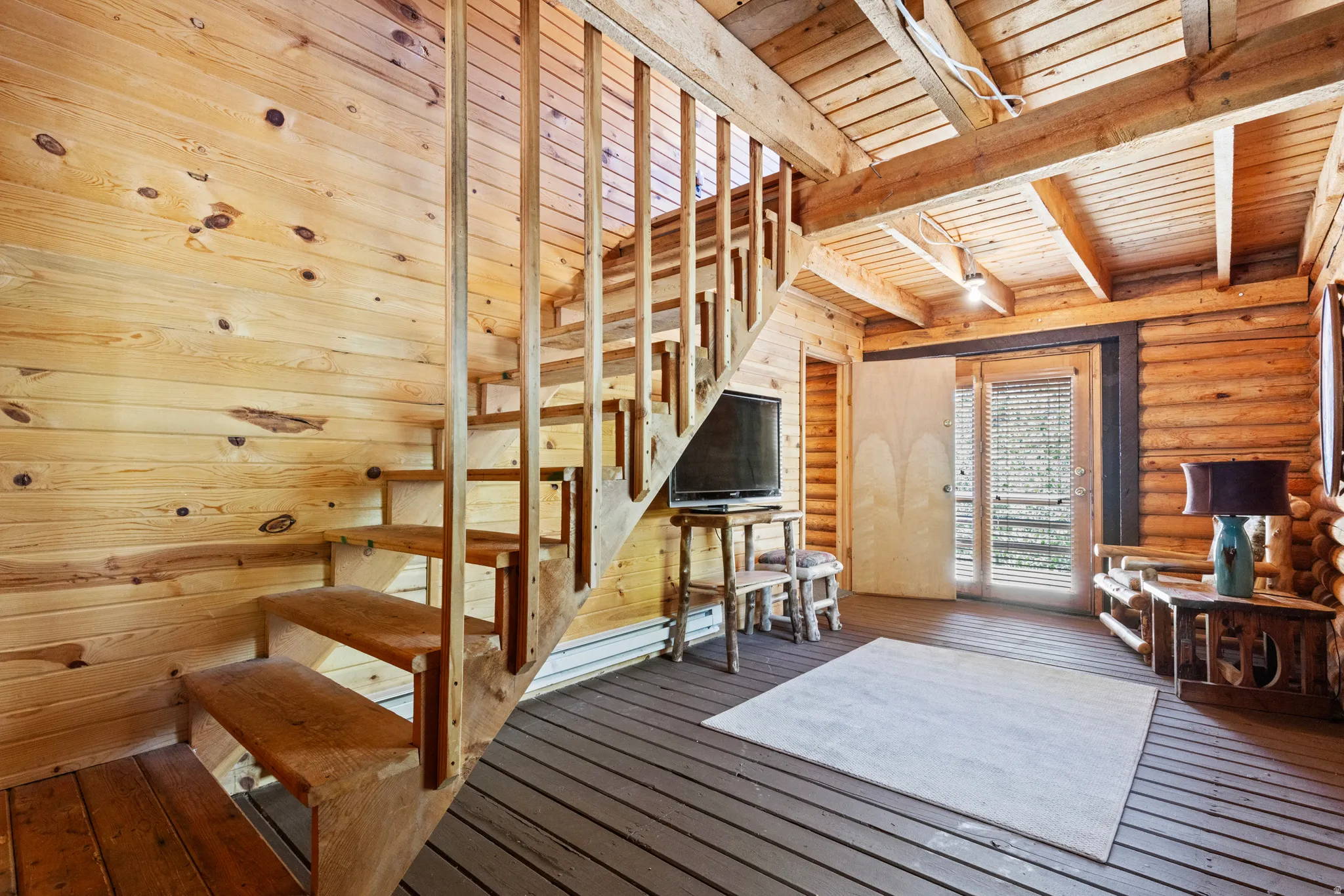 Stairs featuring hardwood / wood-style floors, rustic walls, and a wooden ceiling with exposed beams