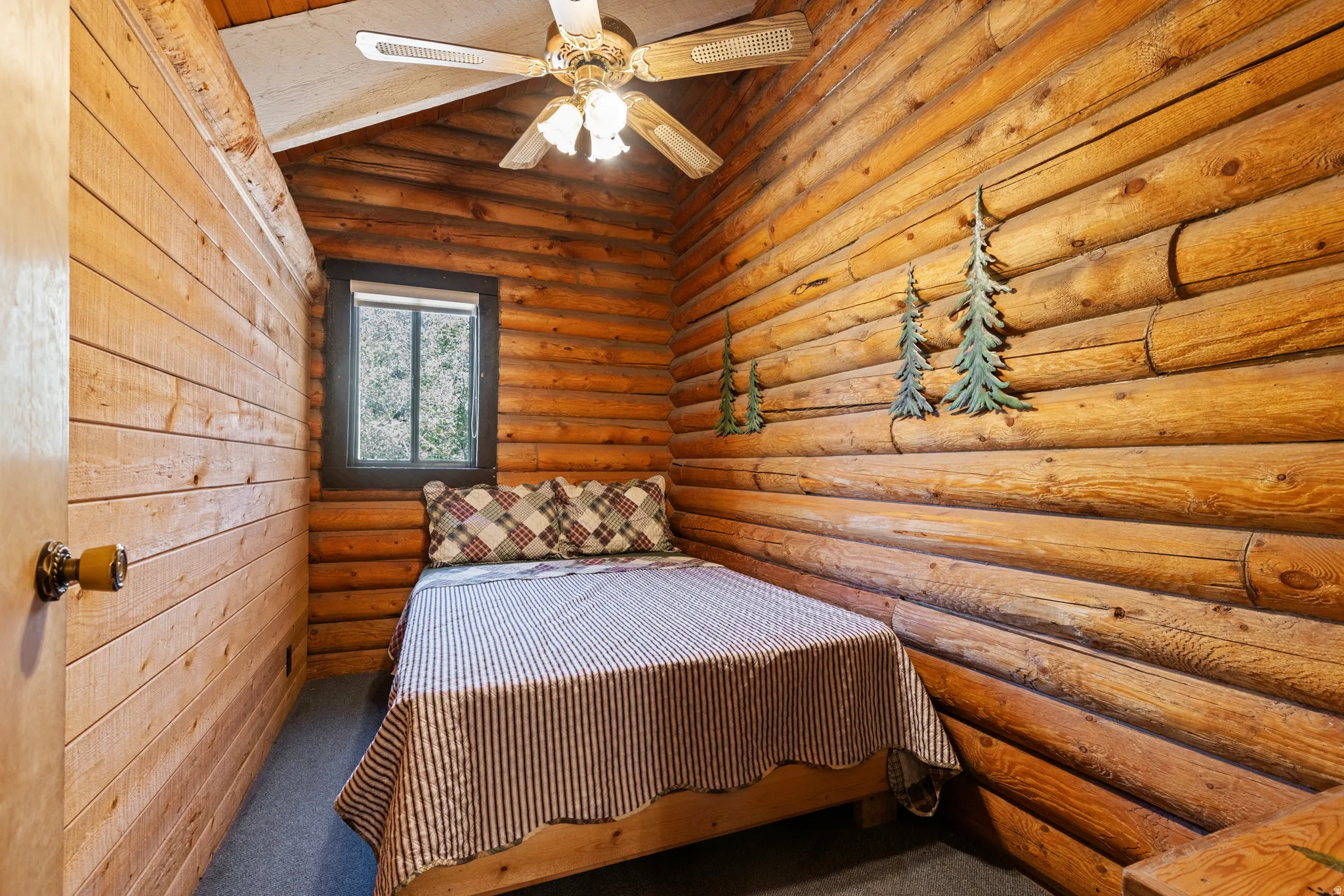 Bedroom featuring log walls, carpet, wooden ceiling, and a ceiling fan