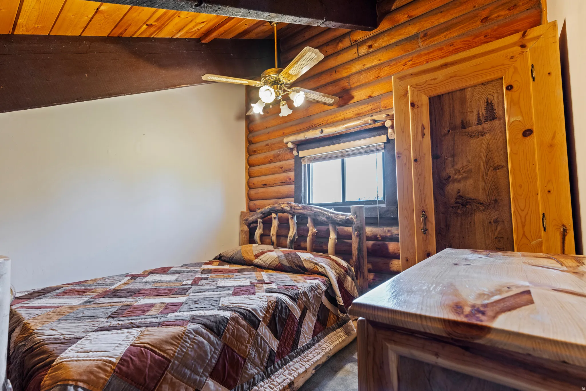Bedroom with log walls, beamed ceiling, and ceiling fan