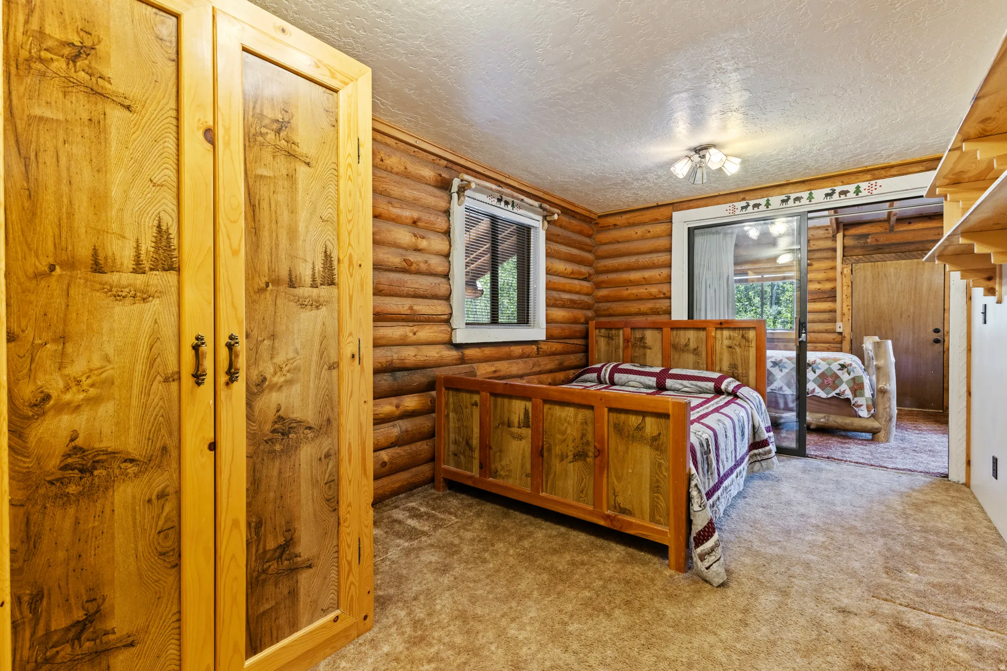 Bedroom featuring log walls, multiple windows, a textured ceiling, and light carpet