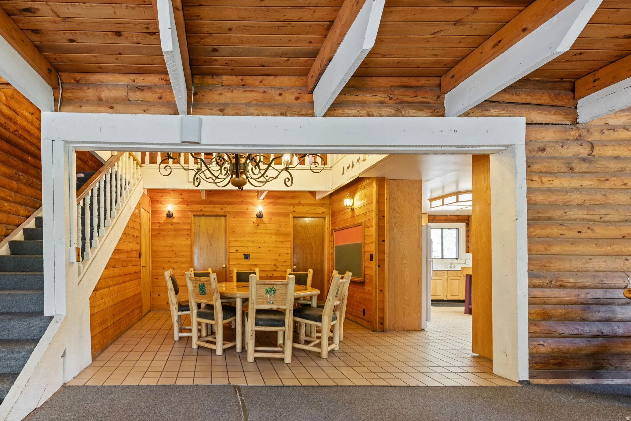 Dining room with log walls, light tile patterned floors, stairway, a wooden ceiling with exposed beams, and light carpet