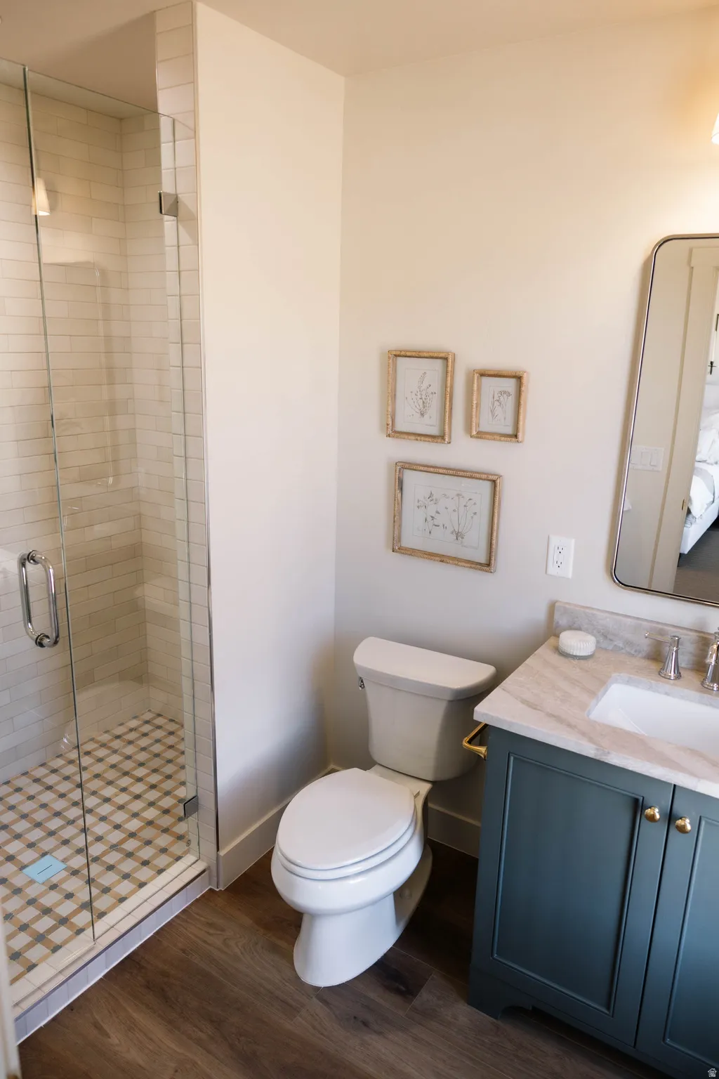 Full bath featuring dark wood finished floors, vanity, and a stall shower
