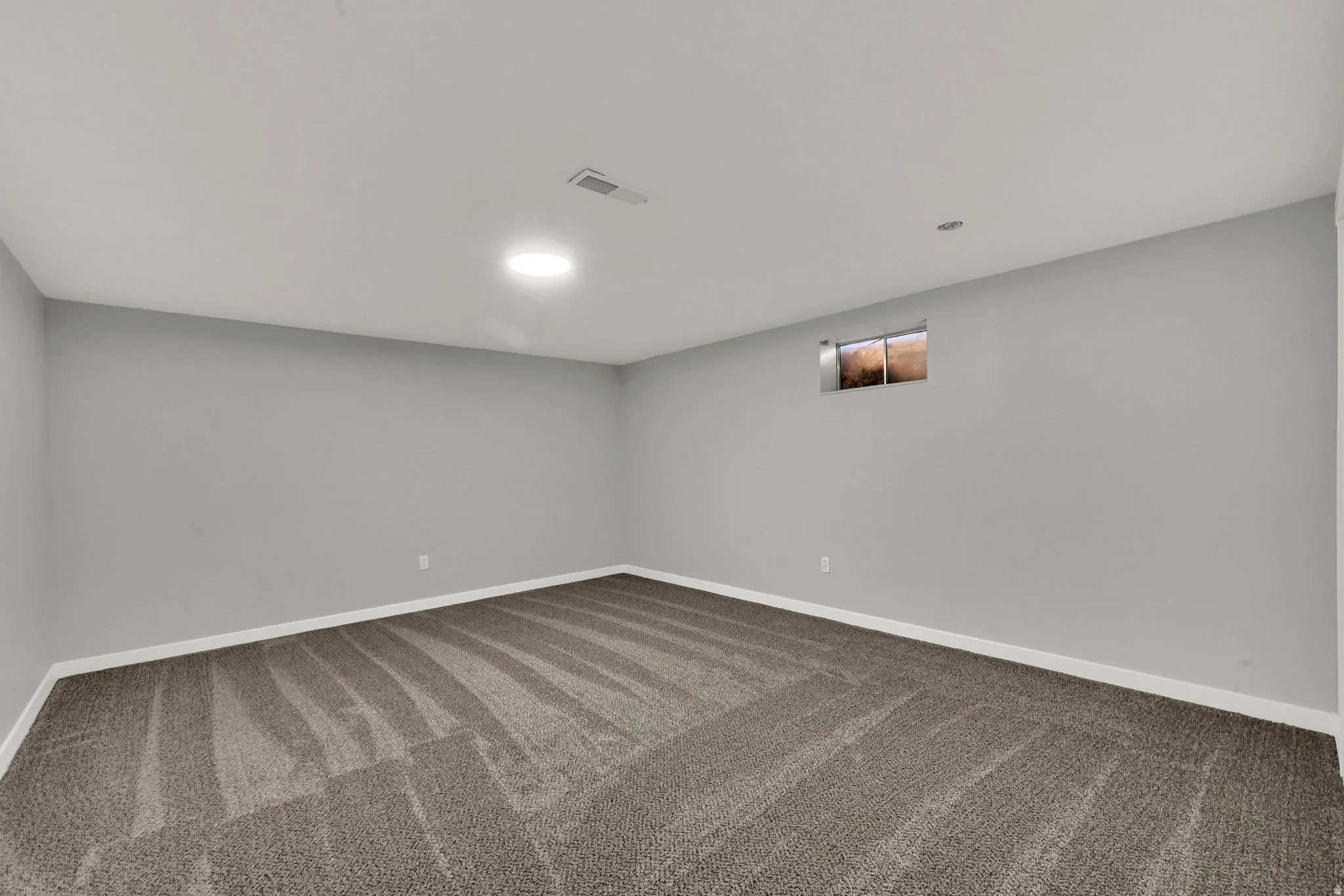 Carpeted spare room featuring baseboards