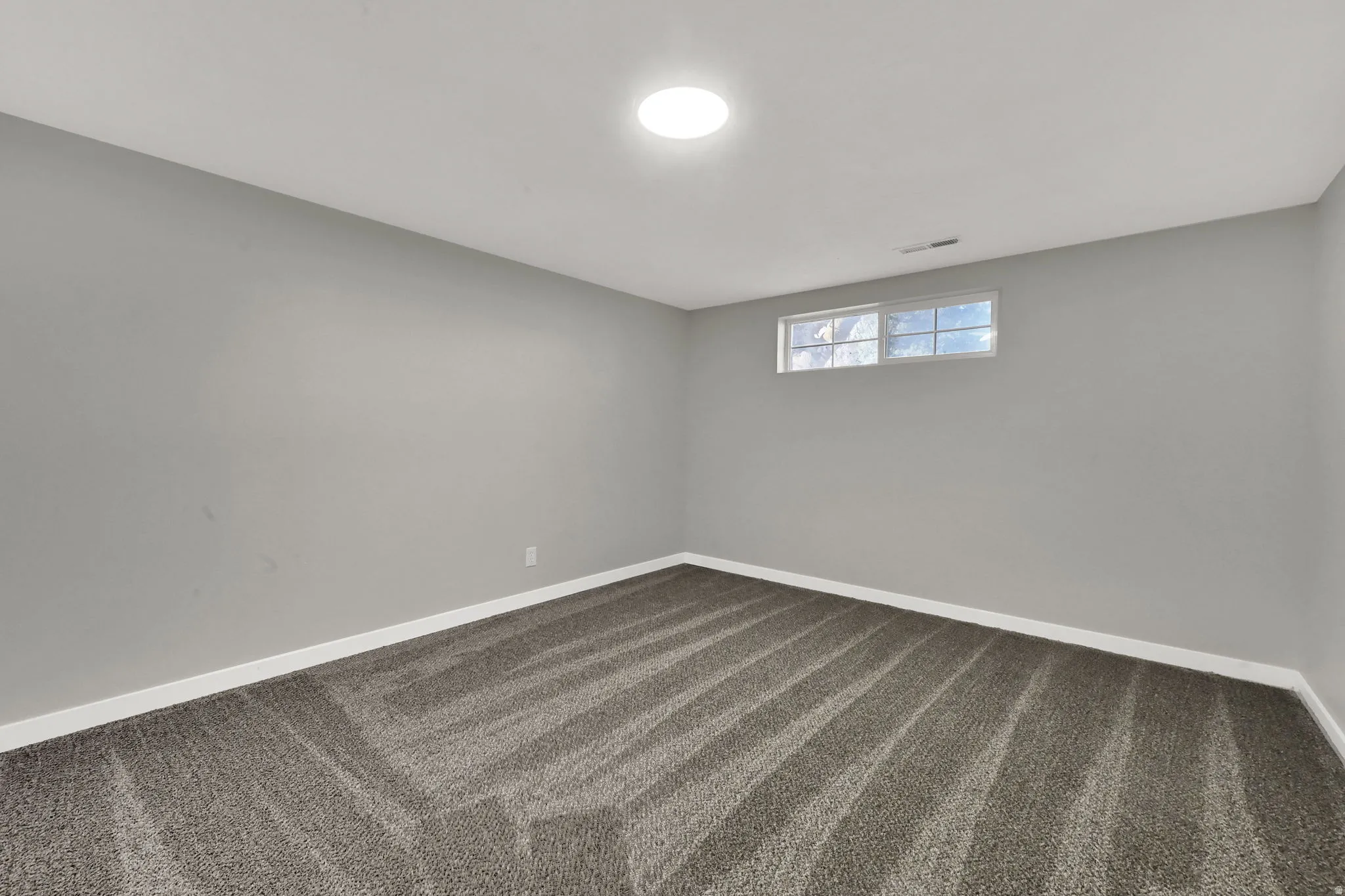 Spare room with dark colored carpet and baseboards
