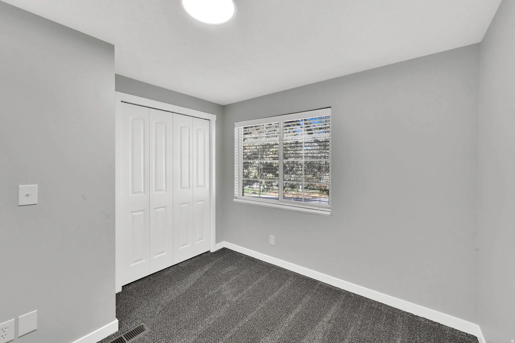 Unfurnished bedroom featuring dark colored carpet and a closet