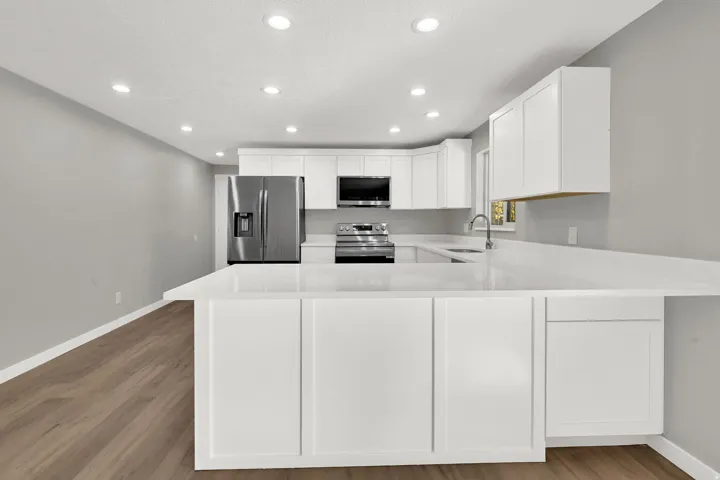 Kitchen featuring a peninsula, white cabinetry, stainless steel appliances, recessed lighting, and light wood-style flooring