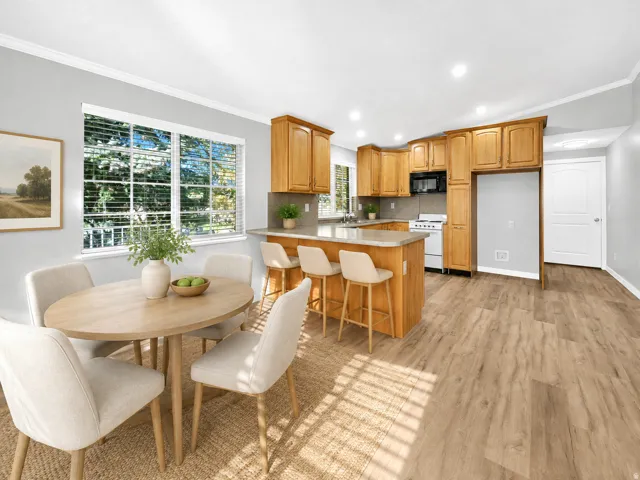 Wood-finish flooring, recessed lighting, wood cabinetry, light-toned countertops, and a white appliance package