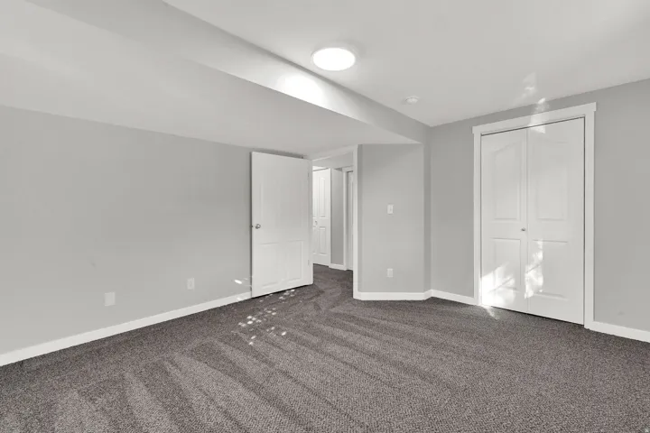 Unfurnished bedroom featuring dark carpet and a closet