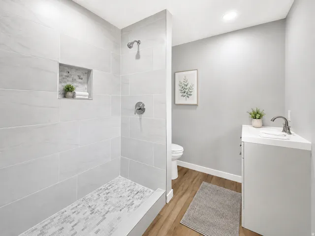 Walk-in shower with light-toned rectangular wall tiles and mosaic floor tiles