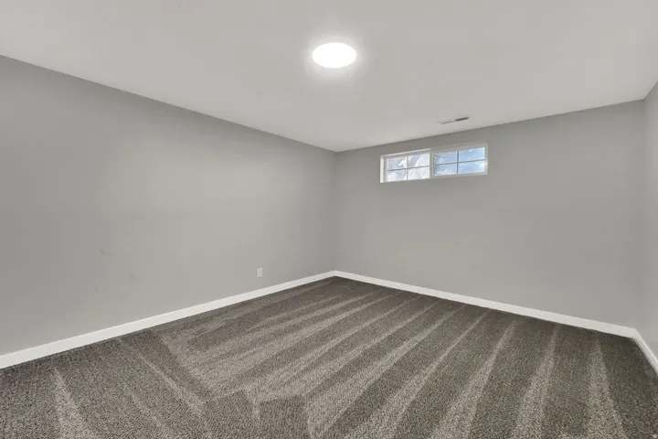 Spare room with dark colored carpet and baseboards