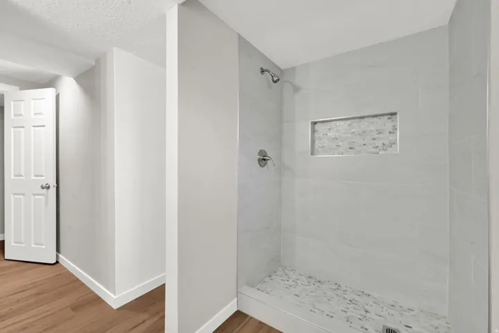 Bathroom featuring a shower stall, wood finished floors, and a textured ceiling