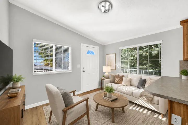 Vaulted ceiling, wood-finish flooring, two windows with blinds, built-in cabinetry, and a countertop
