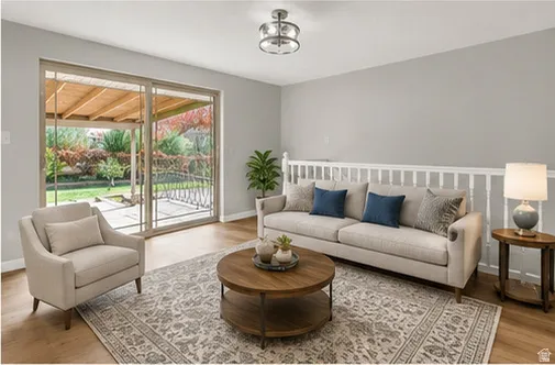 Sliding glass doors opening to the exterior patio, overhead lighting fixture, wood-finish flooring, interior railing with white balusters, and light gray wall paint