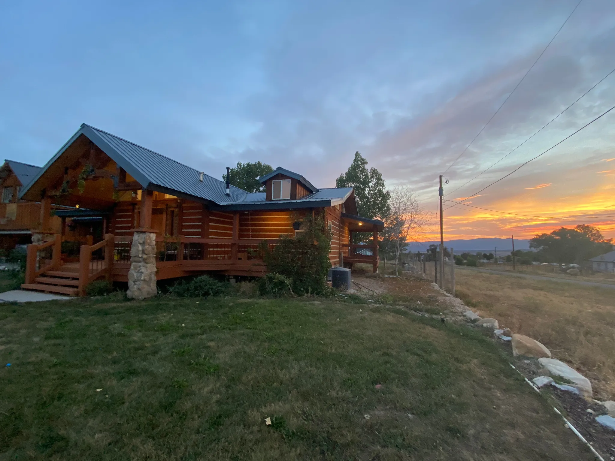 Back of property at dusk featuring a metal roof, a yard, and a deck