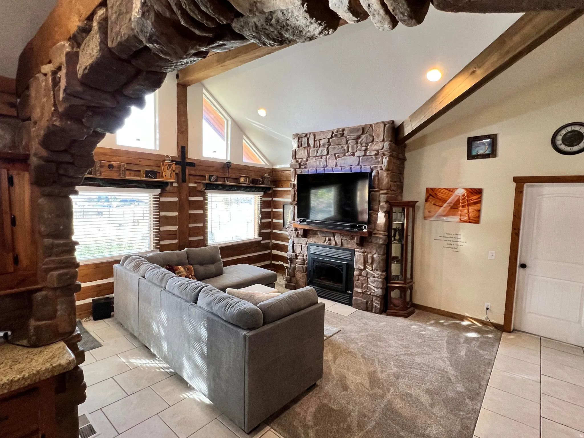 Living area with tile patterned flooring, beamed ceiling, high vaulted ceiling, a fireplace, and recessed lighting