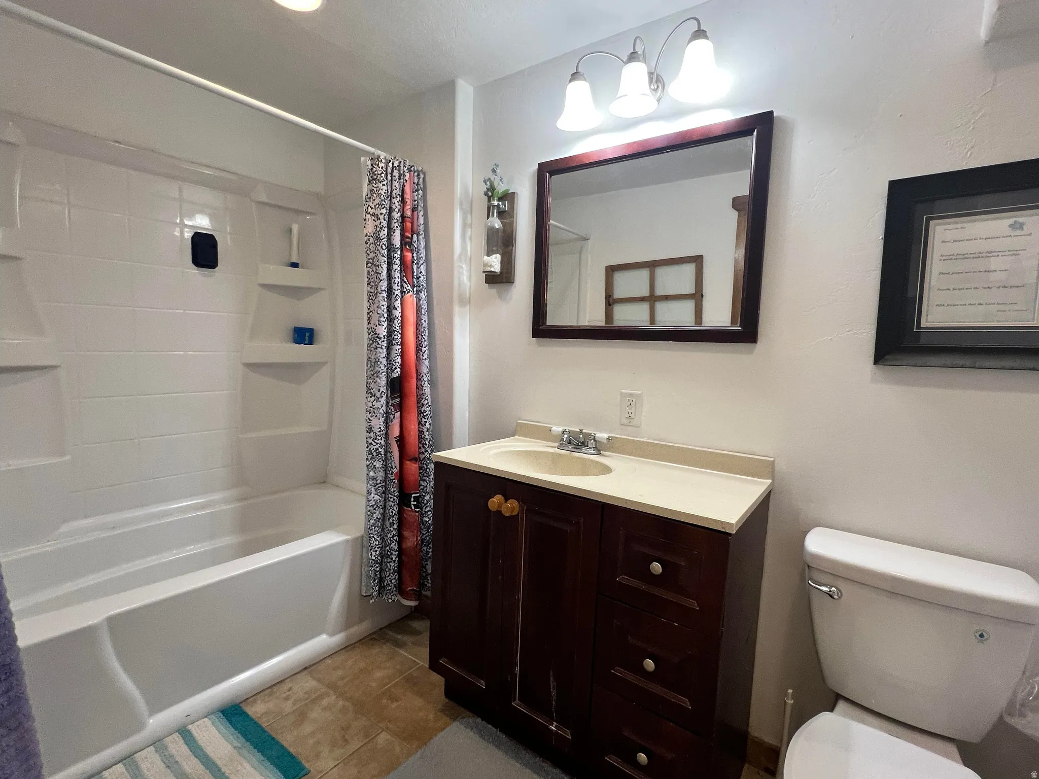 Bathroom featuring shower / bath combo with shower curtain, vanity, and dark tile patterned floors